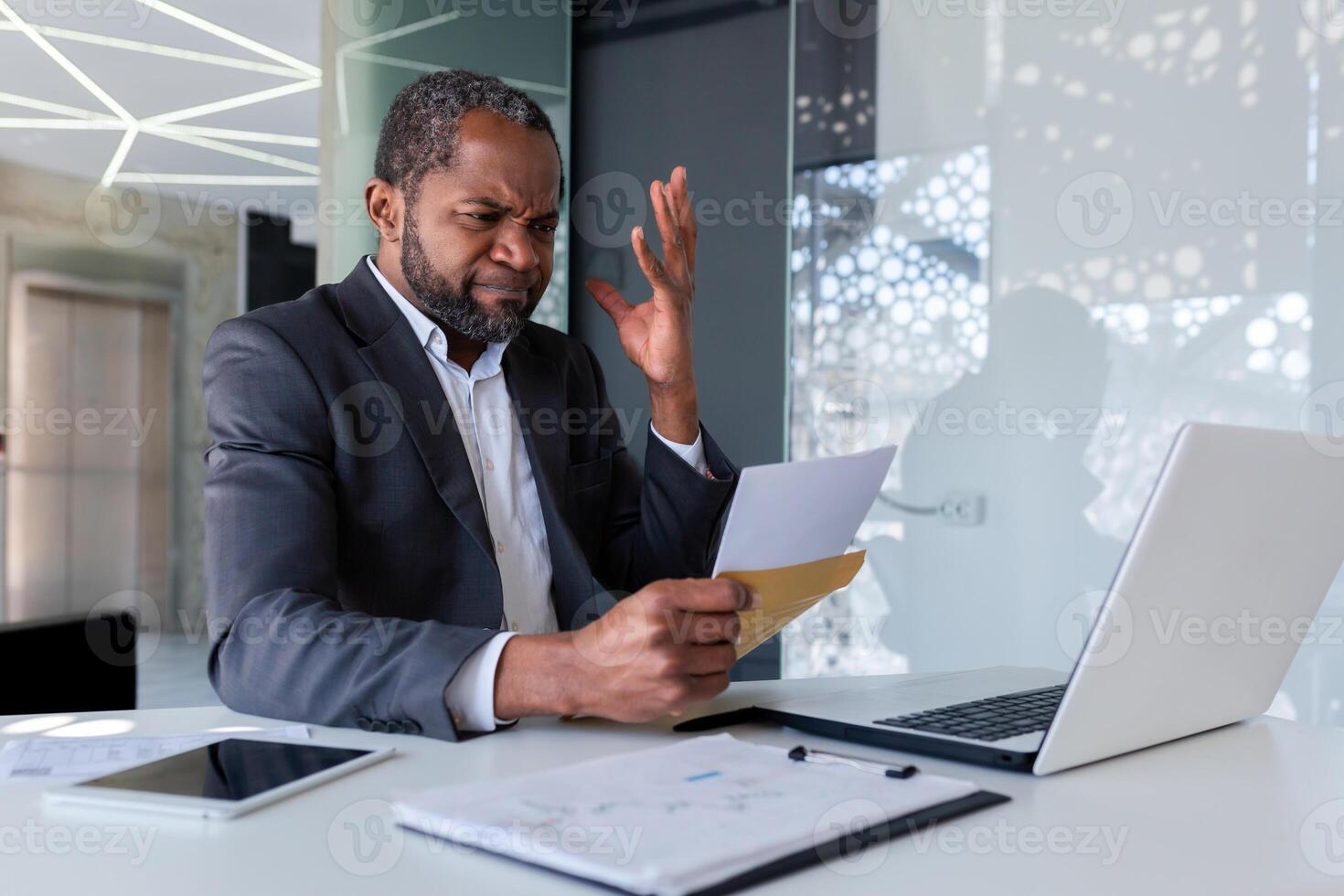 nervioso y trastornado empresario en oficina a lugar de trabajo recibido correo sobre notificación mensaje con malo Noticias bancarrota, africano americano hombre triste y pensativo leyendo documento. foto