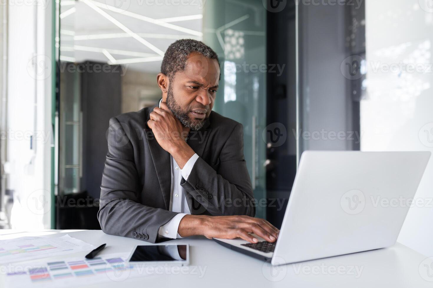 Mature senior thinking businessman at workplace inside office, african american gray haired boss working with laptop inside office. photo