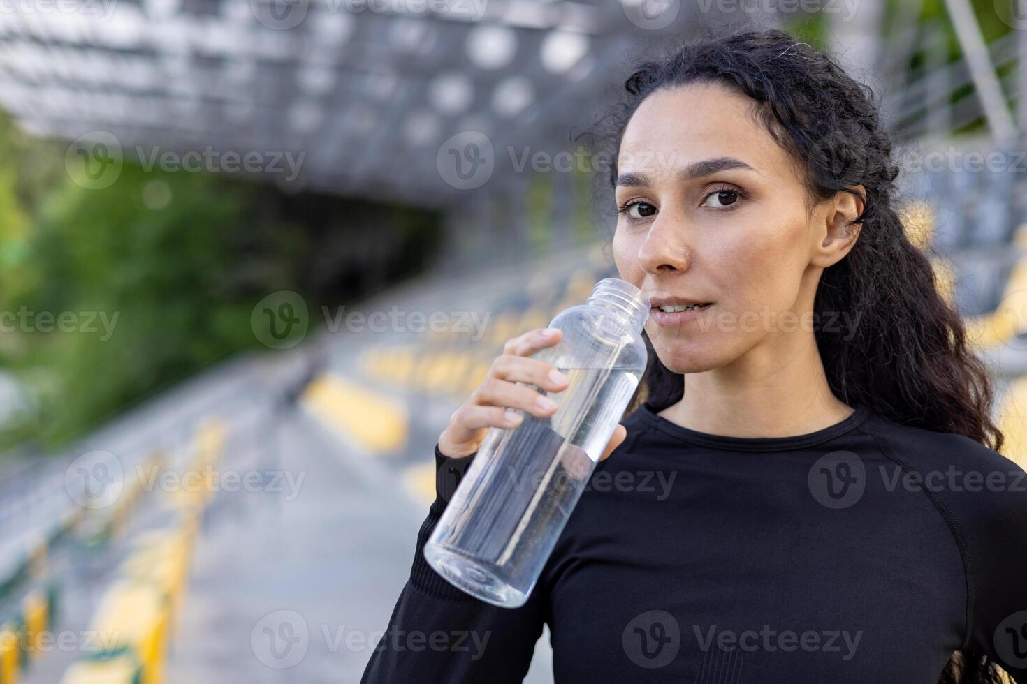 un joven activo mujer toma un agua descanso al aire libre después hacer ejercicio, encarnando un sano estilo de vida y aptitud física. foto