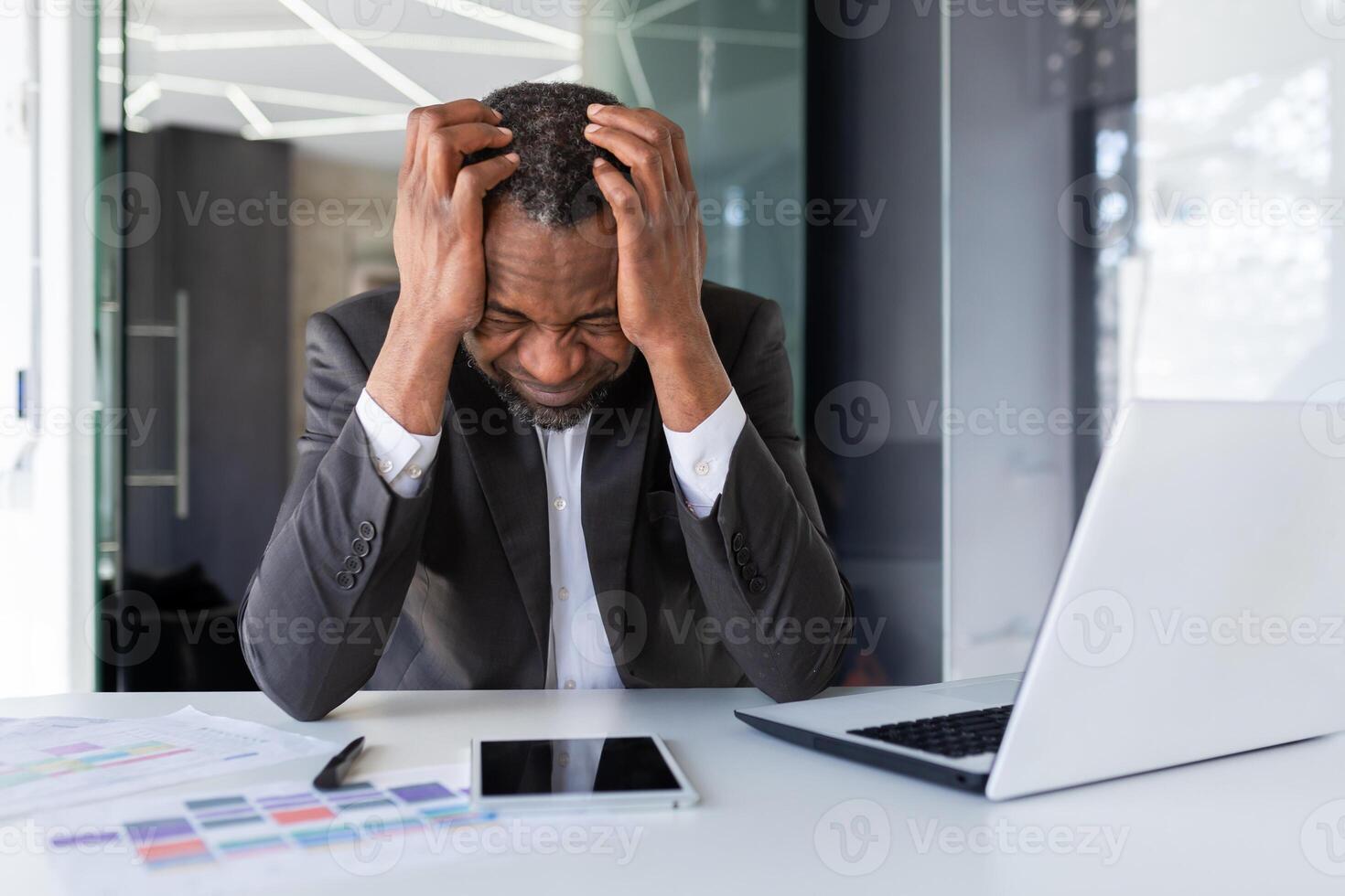 African american mature adult businessman upset in depression at workplace, senior man working in middle of office, unhappy with results of financial achievement banker investor photo