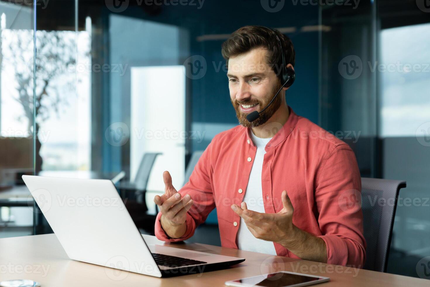 Mature successful businessman with call headset working inside office, man consulting online clients, talking with colleagues on online remote meeting, sitting at workplace with laptop. photo