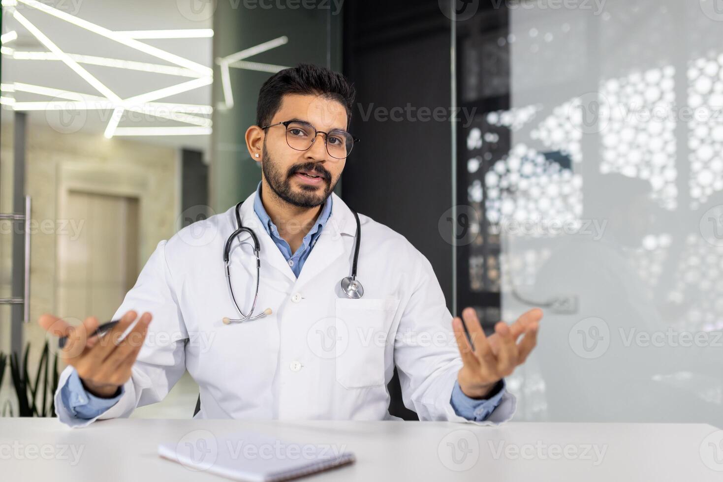 A doctor is sitting at a desk with a clipboard and a pen photo