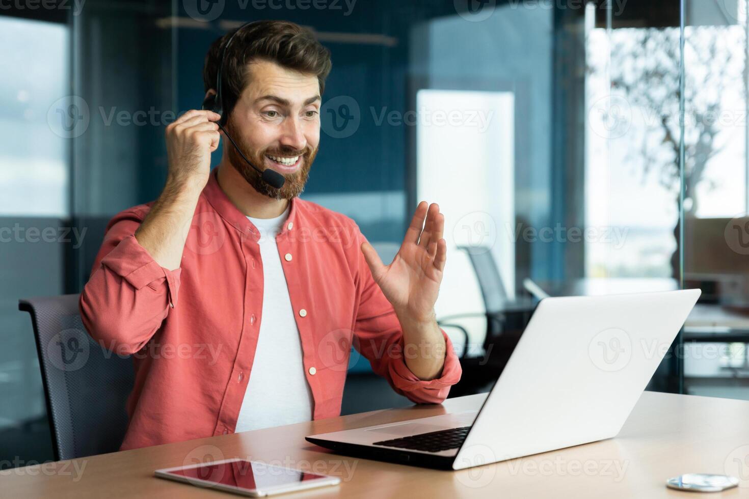 Mature successful businessman with call headset working inside office, man consulting online clients, talking with colleagues on online remote meeting, sitting at workplace with laptop. photo