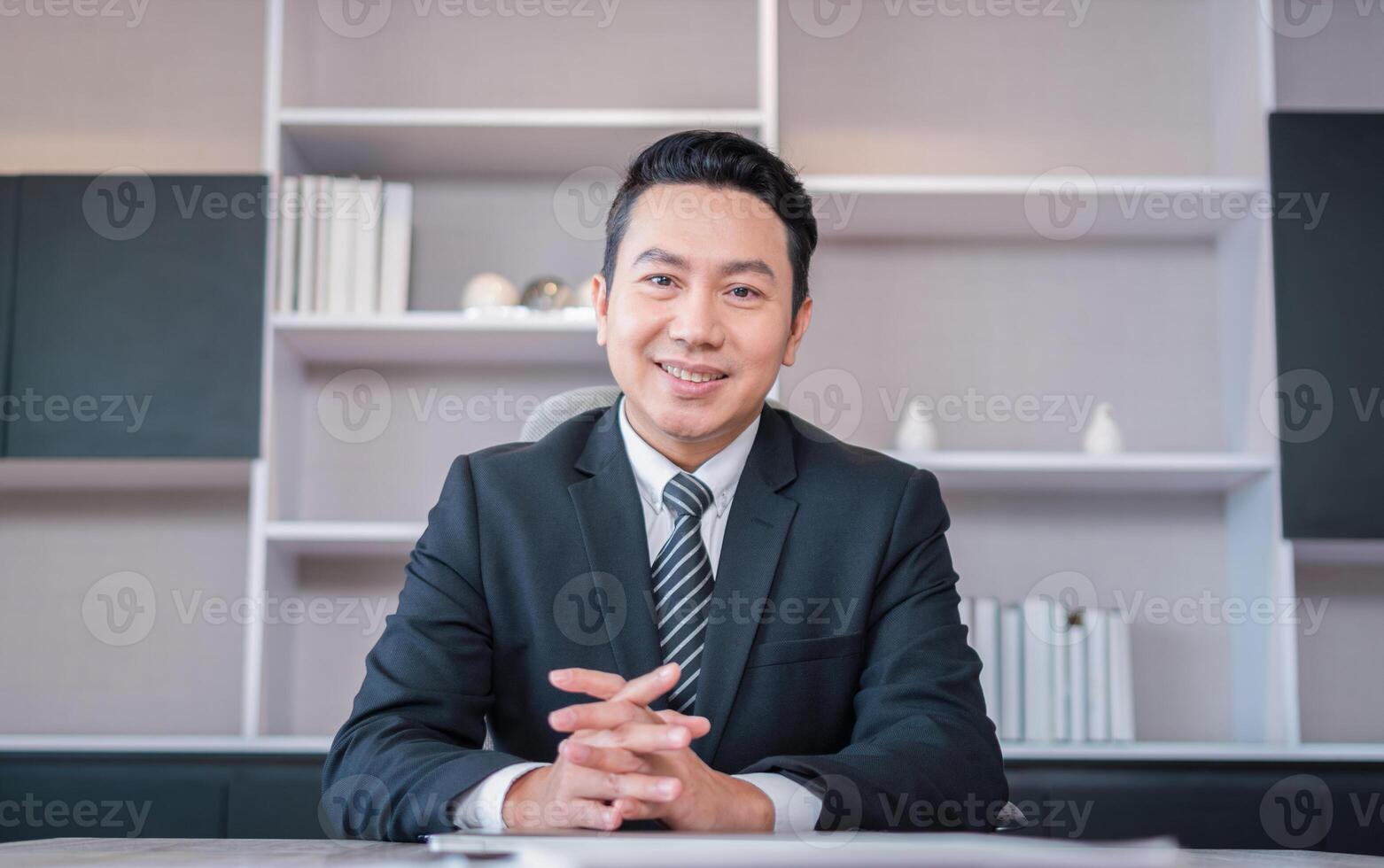 Asian businessman sitting at office desk and looking at camera photo