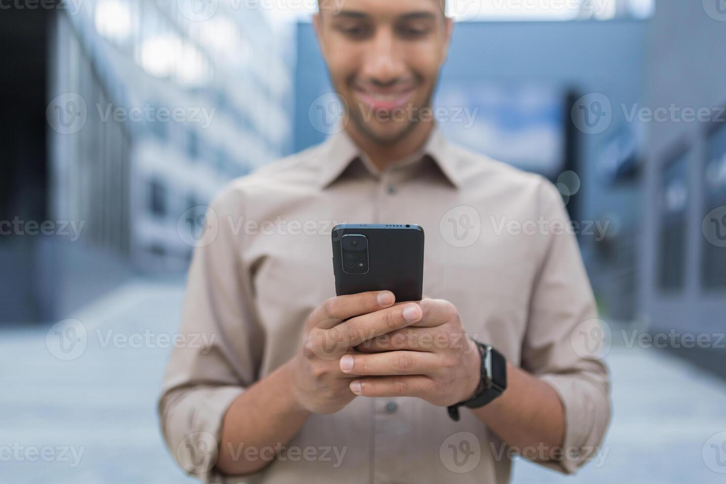 Close up photo selective focus african american man typing message on phone smiling and happy businessman using smartphone
