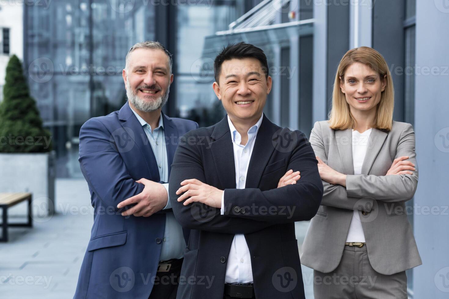 exitoso diverso negocio equipo, Tres trabajadores sonriente y mirando a cámara, sueño equipo con asiático jefe fuera de oficina edificio, colegas en negocio trajes foto