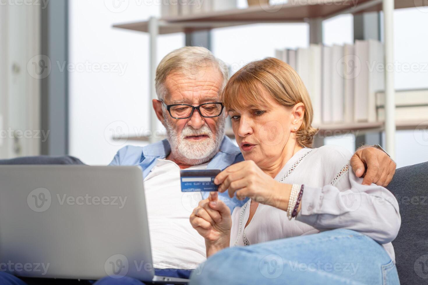 Senior couple with laptop shopping online at home and paying with credit card photo