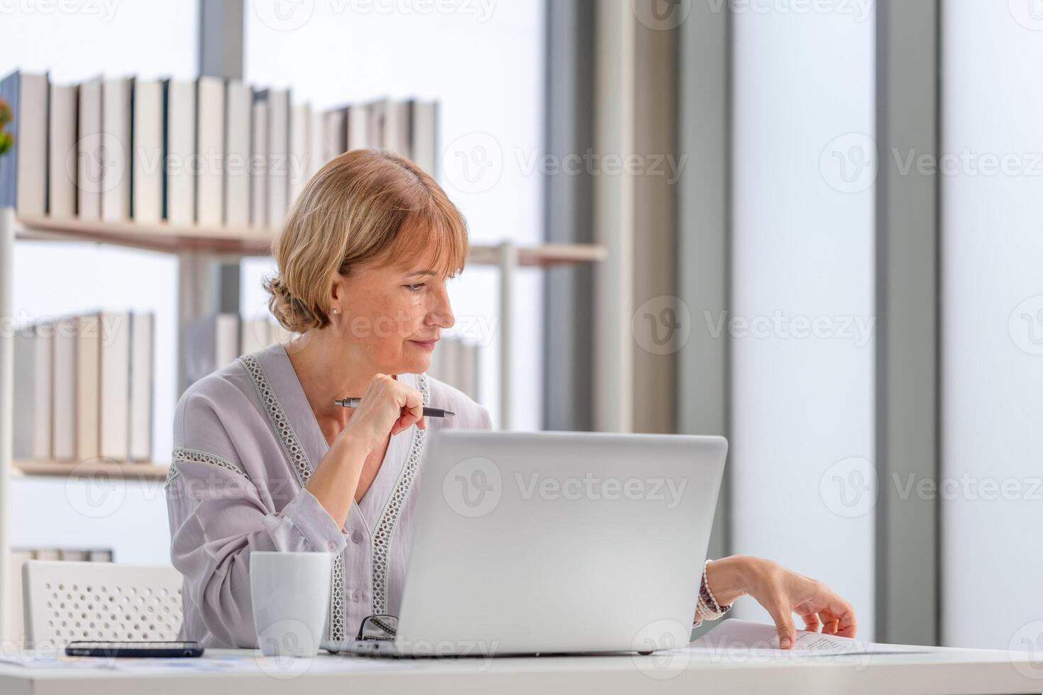 Woman using laptop and smartphone at home, Mature woman checking their bills photo