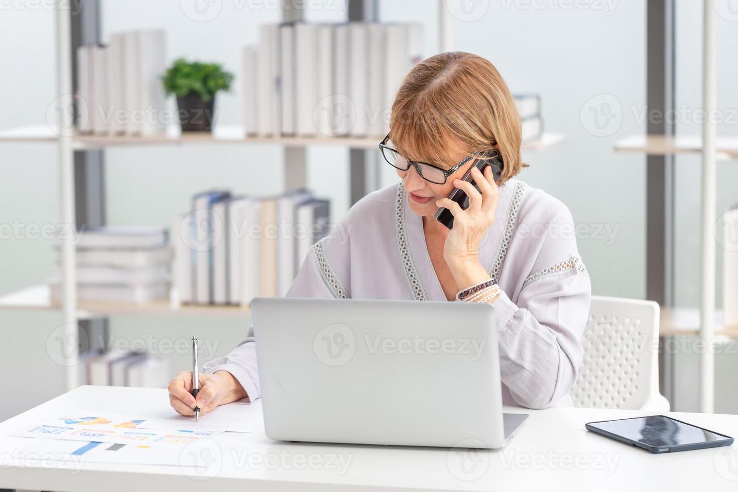 Mature woman checking their bills, Woman using laptop and smartphone at home photo