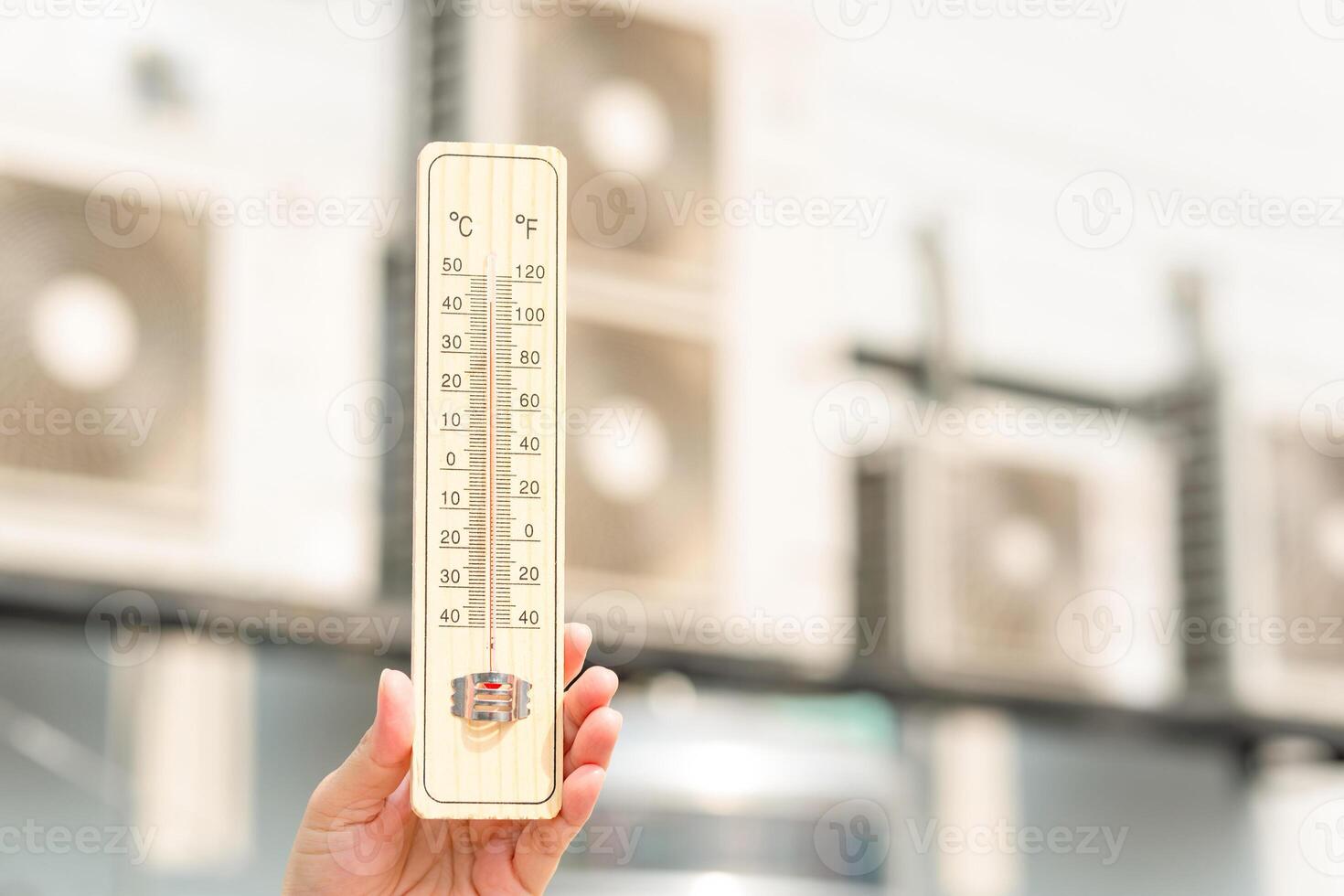 Hot temperature, Hand holding thermometer with blurred air conditioner compressor photo