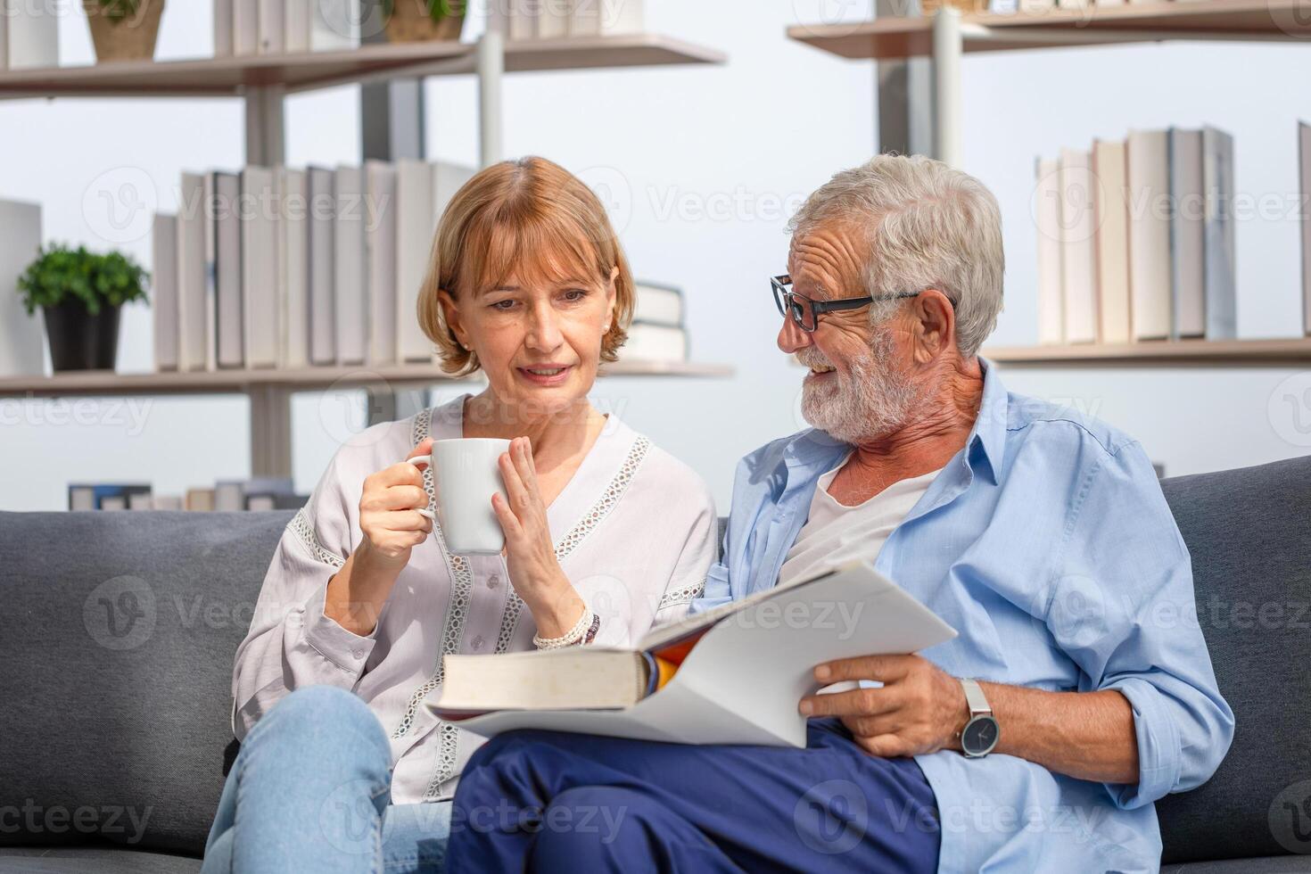 mayor hombre y mujer leyendo un libro y disfrutando café, alegre Pareja gasto hora juntos en el vivo habitación foto