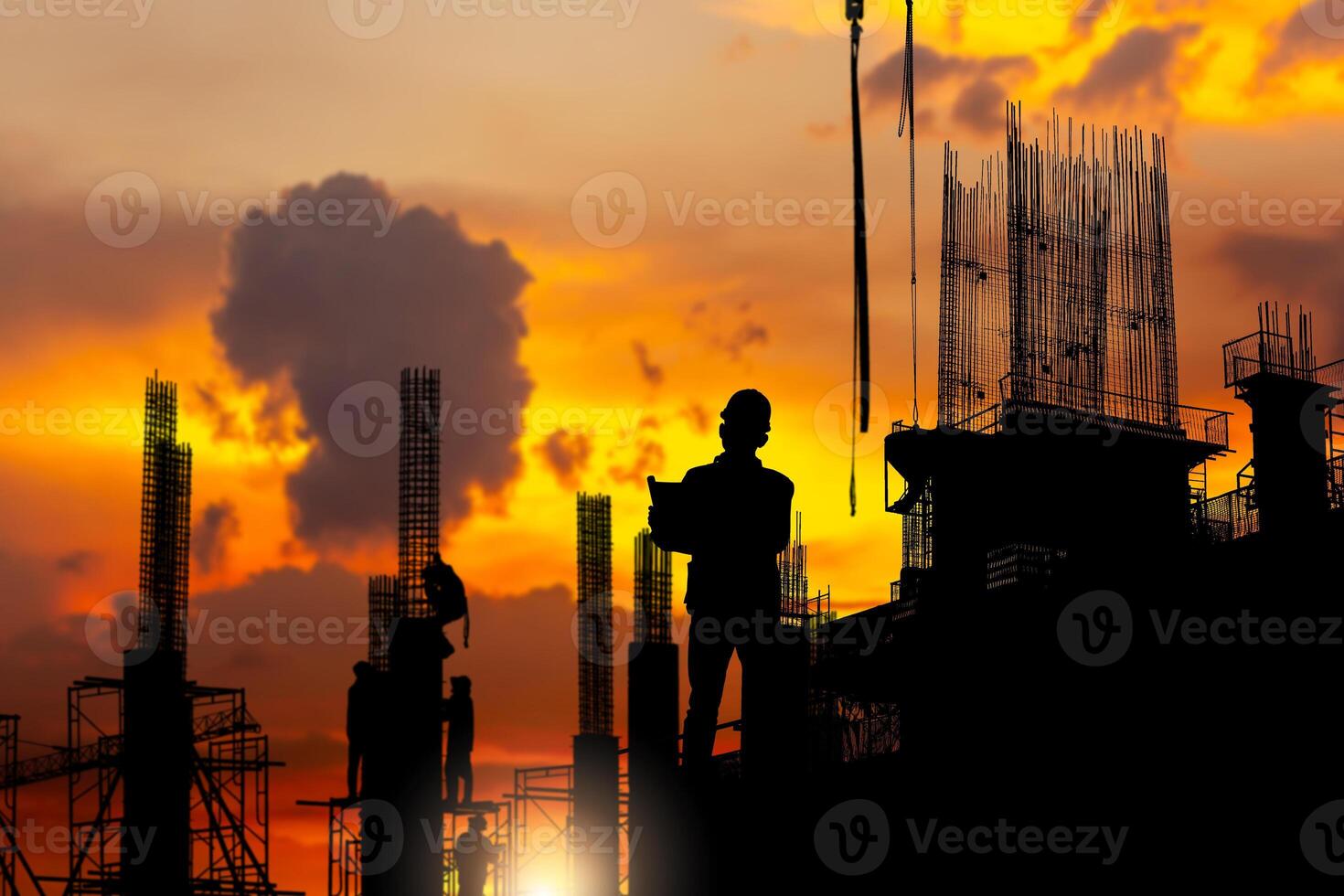 Silhouette of Engineer and worker team checking project at building site background, a construction site with sunset photo