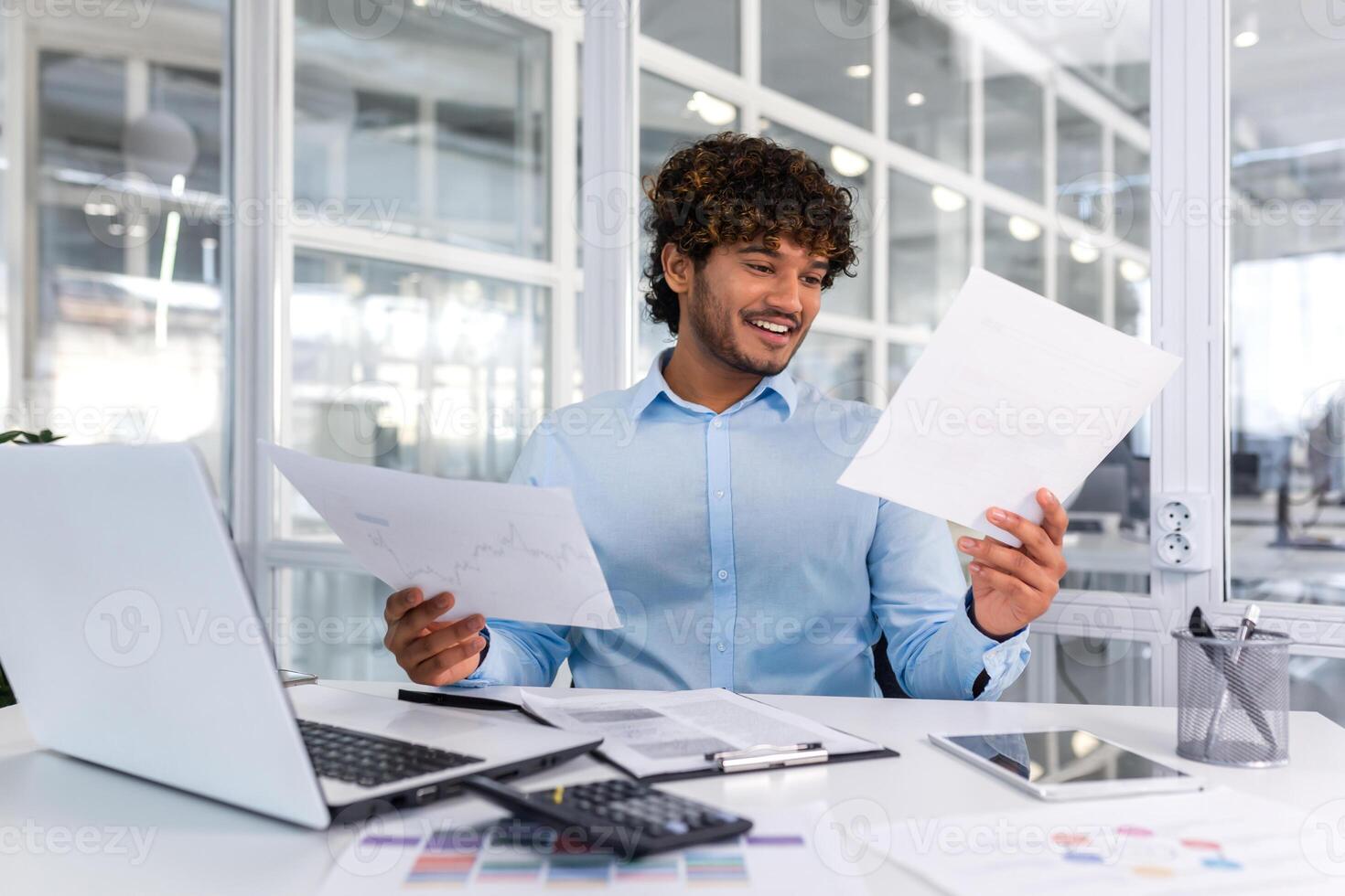 Successful financier accountant working inside office with laptop and documents, man satisfied with audit results smiling and reading financial reports, businessman using laptop for paperwork. photo