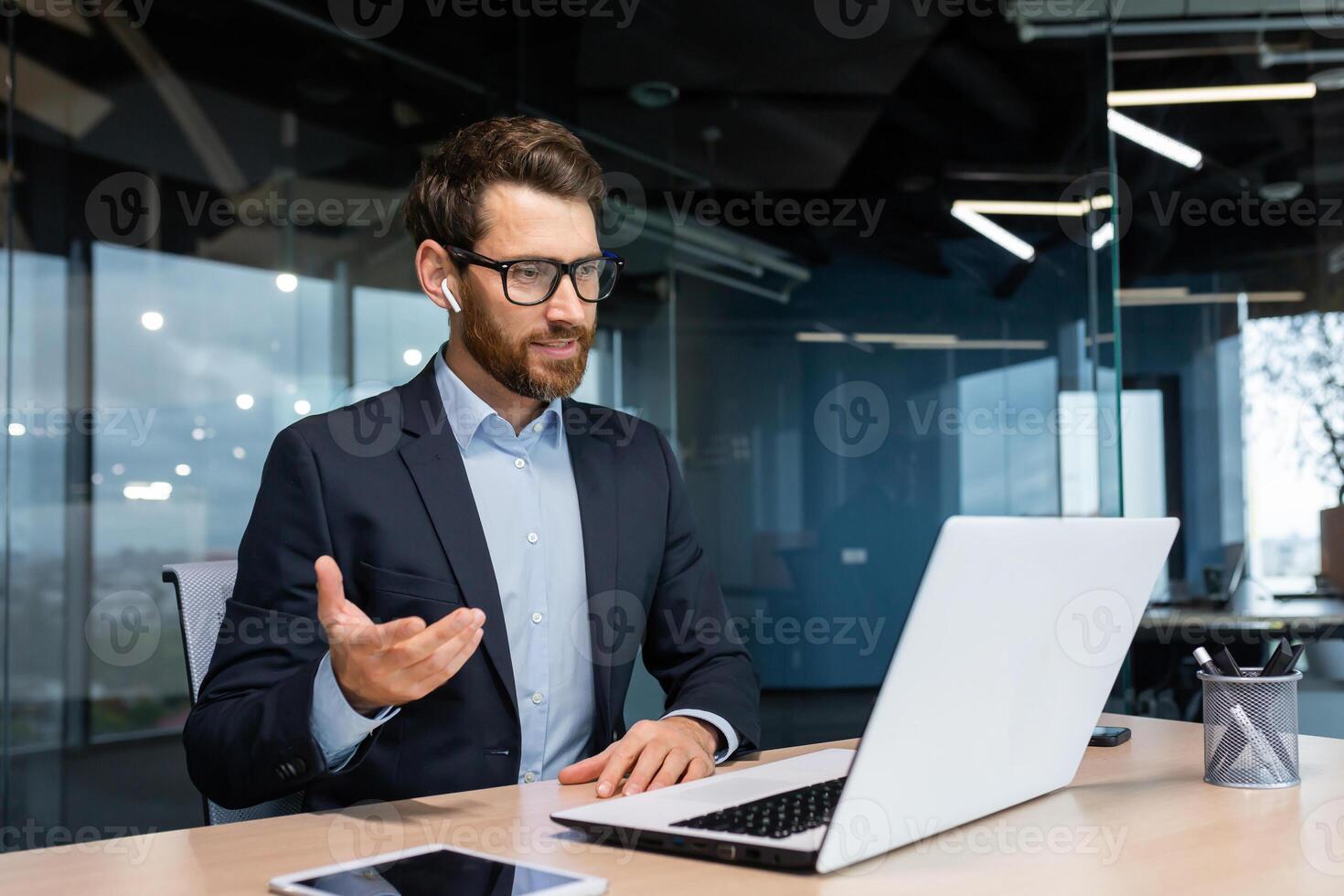 Online meeting, mature businessman inside office talking remotely online with colleagues and partners, call senior male executive using laptop to communicate. photo