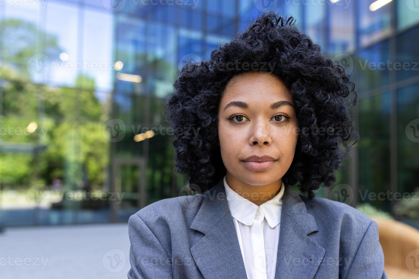 retrato de un grave africano americano hembra estudiante en pie fuera de instalaciones vistiendo un traje y mirando con confianza a el cámara. de cerca foto. foto