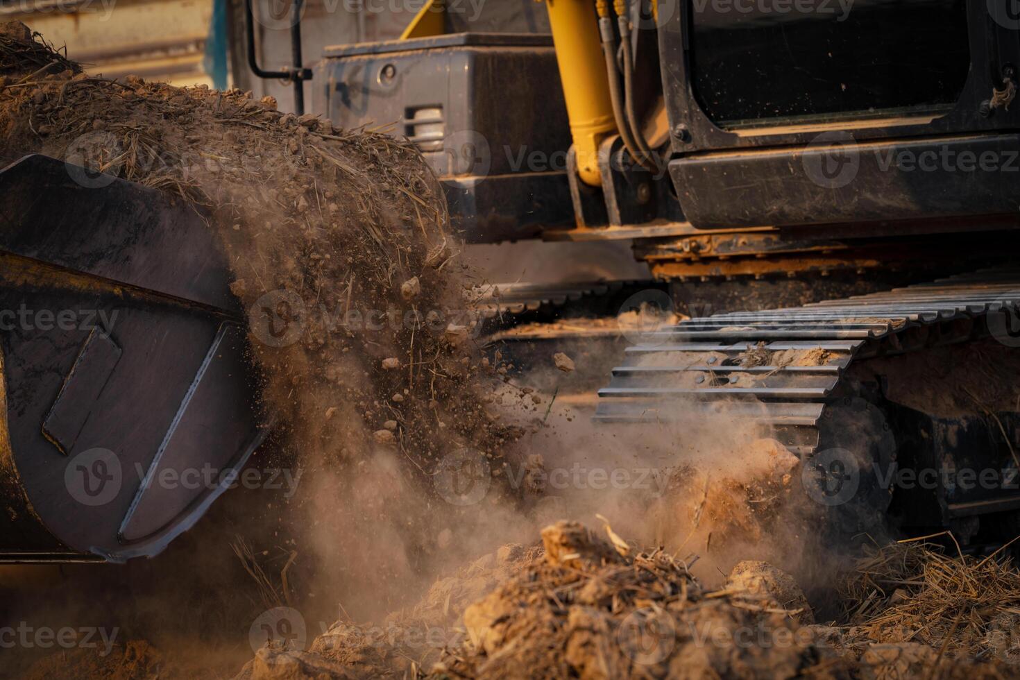Selective focus on metal bucket teeth of backhoe digging soil. Backhoe working by digging soil at construction site. Crawler excavator digging on soil. Earth moving machine. Excavation vehicle. photo