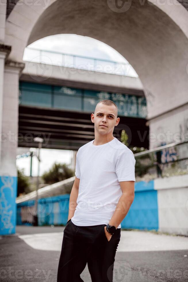 A man in a white shirt stands in front of a blue and white wall photo