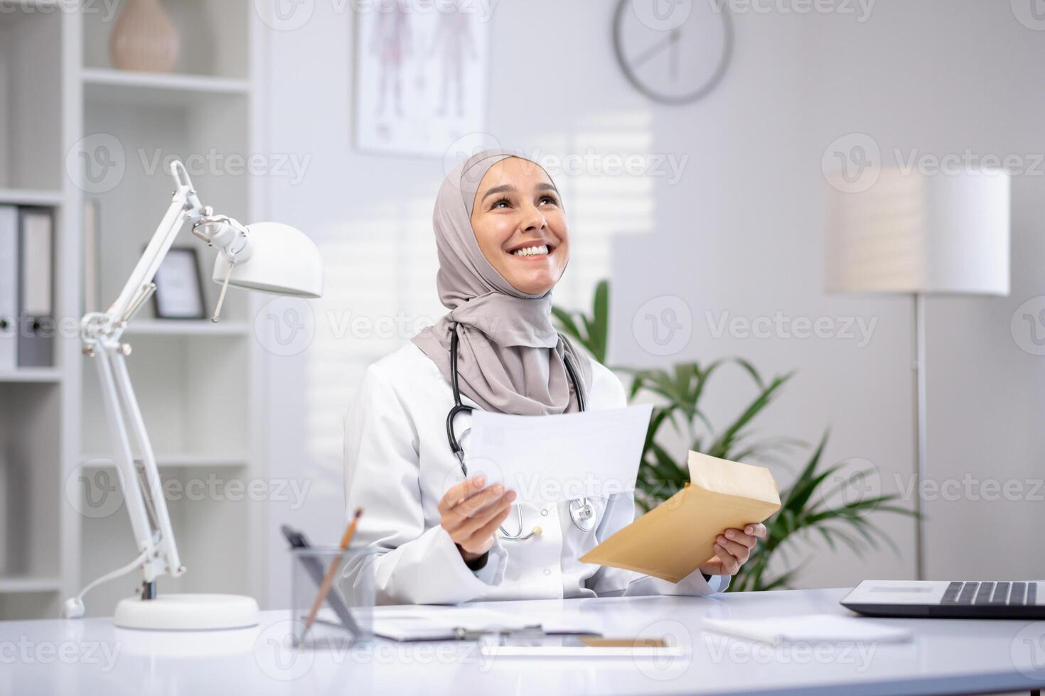 sonriente hembra musulmán médico en un hijab y blanco Saco participación documentos en un moderno clínica oficina, exhibiendo profesional cuidado de la salud. foto