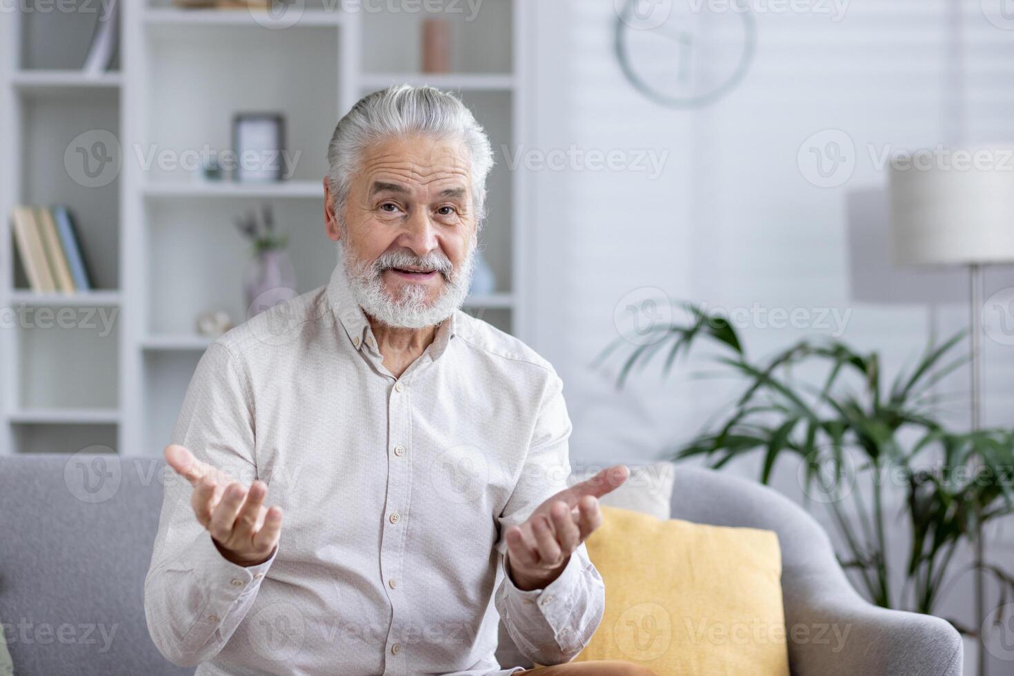 A poised senior man in a living room, comfortably engaging in a call with friends or family, portraying connectivity and modern communication. photo