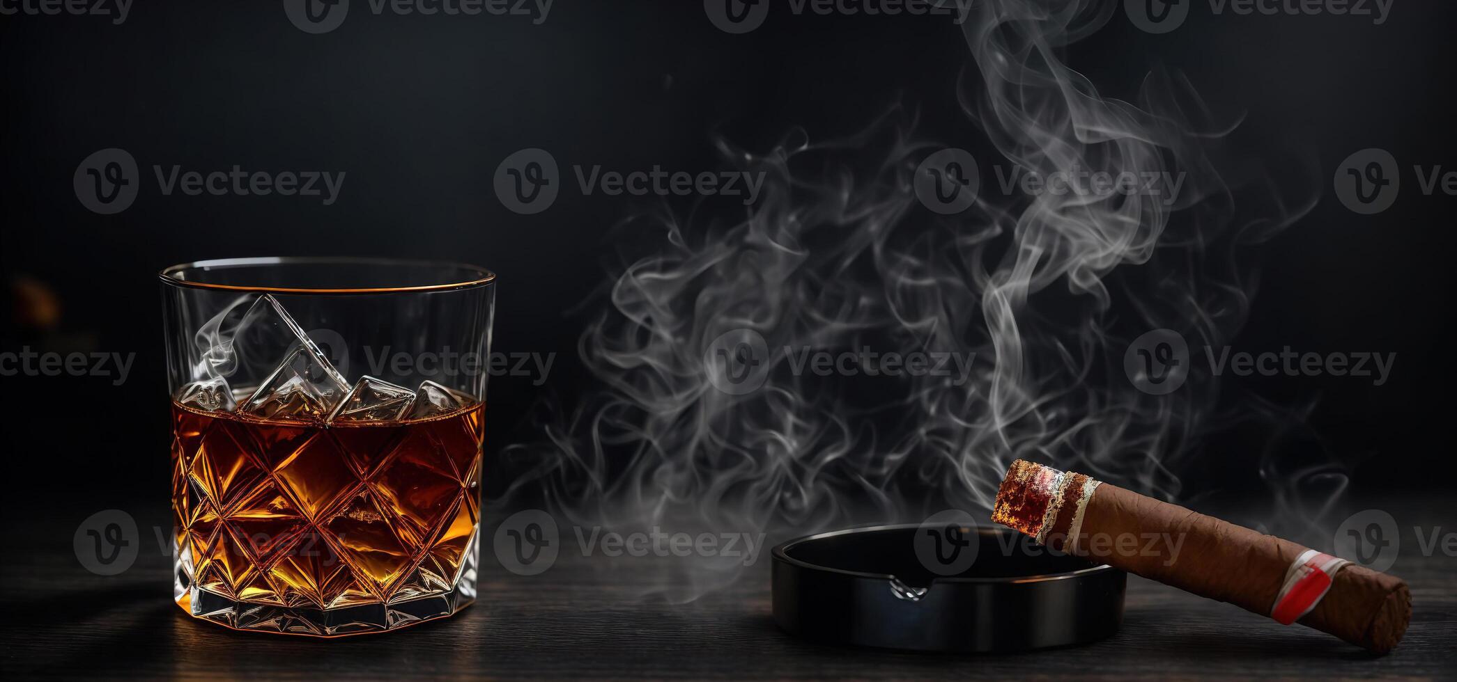 A glass of whiskey with a smoking cigar and an ashtray on a wooden background photo