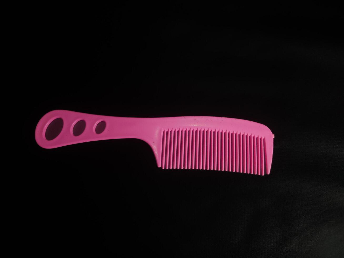 photography of a pink comb on a black background photo