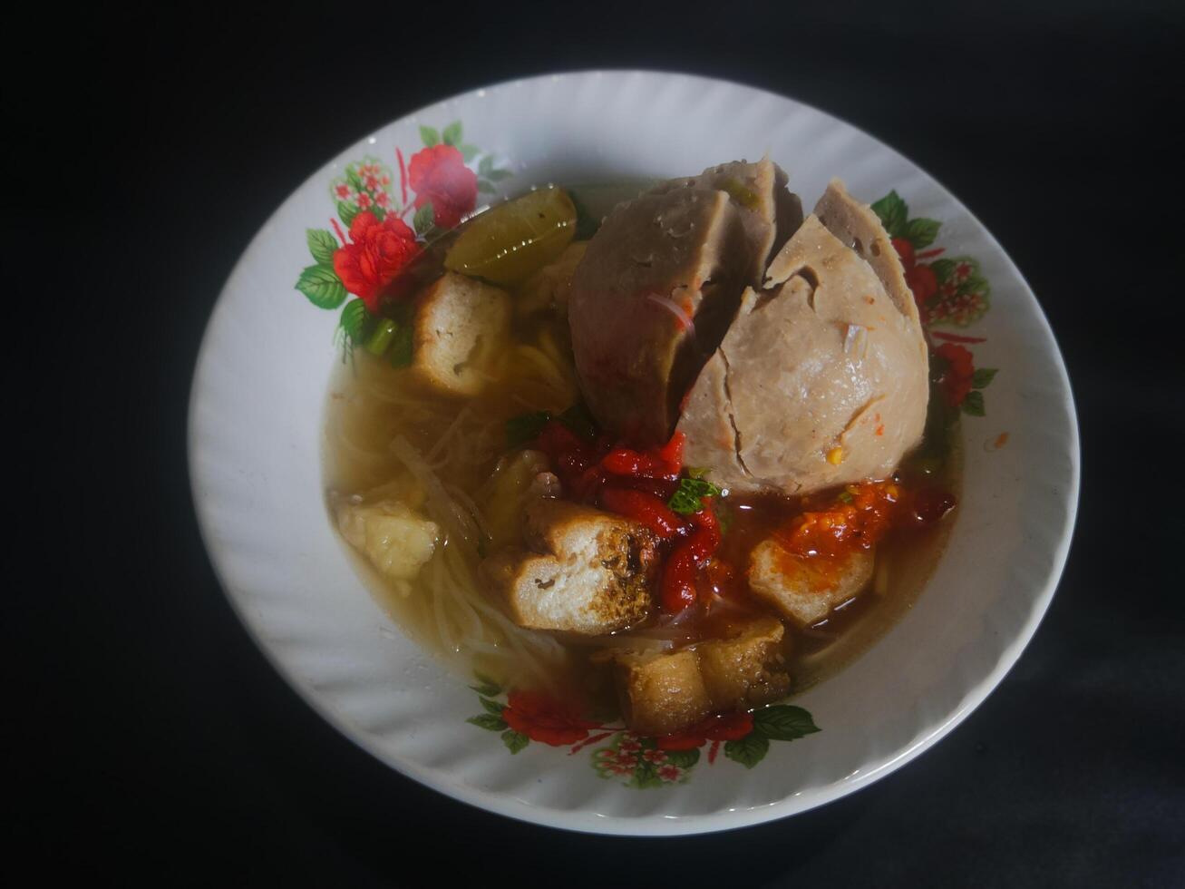 Photography of jumbo meatballs food from Indonesia on a bowl on a black background photo