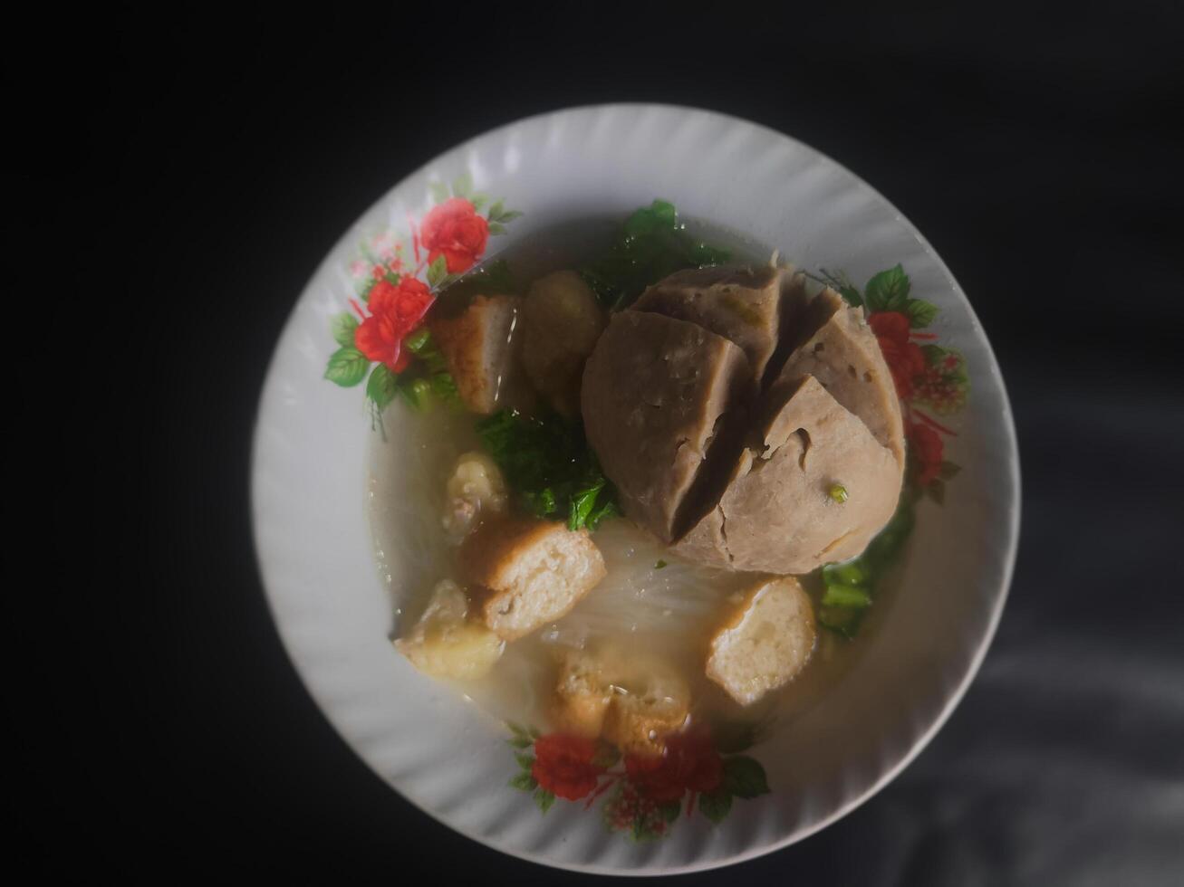 Photography of jumbo meatballs food from Indonesia on a bowl on a black background photo
