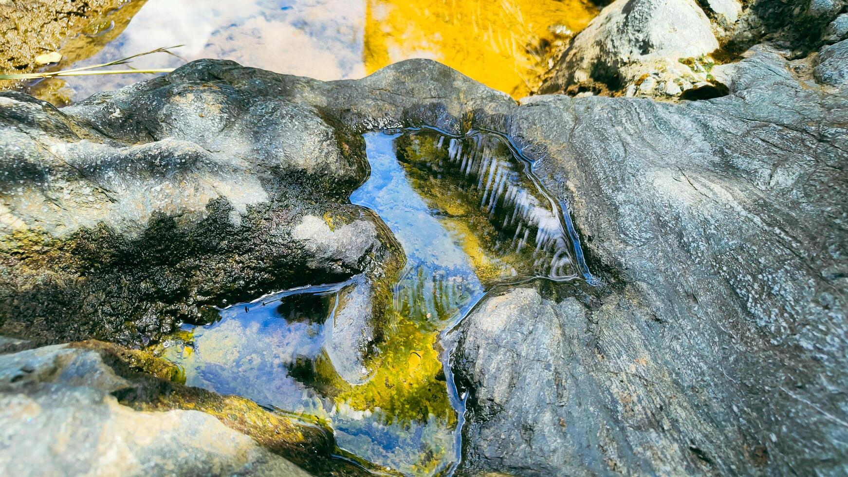 photography of puddles of water between river rocks photo