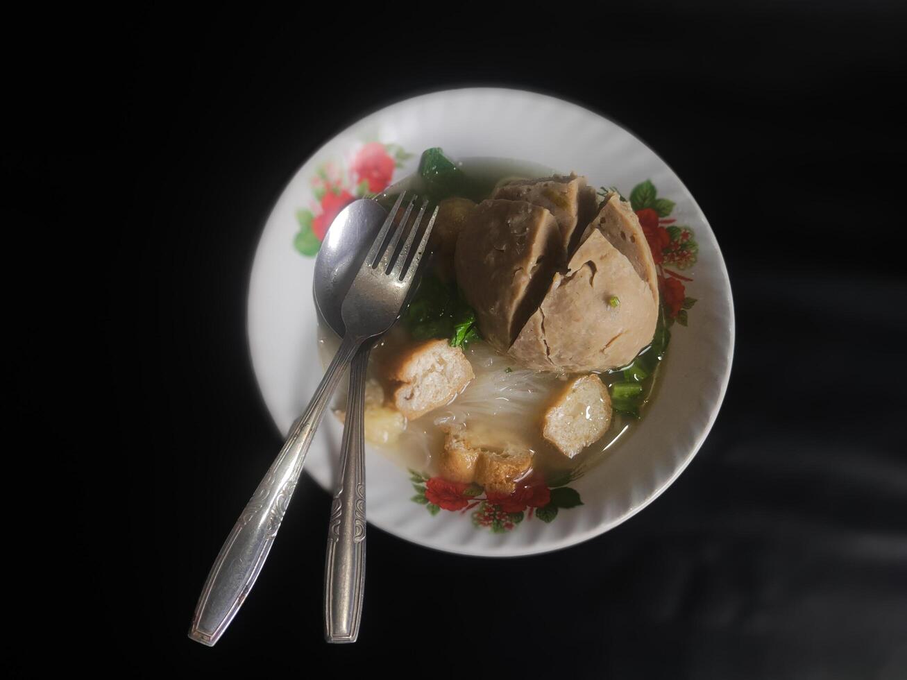Photography of jumbo meatballs food from Indonesia on a bowl on a black background photo