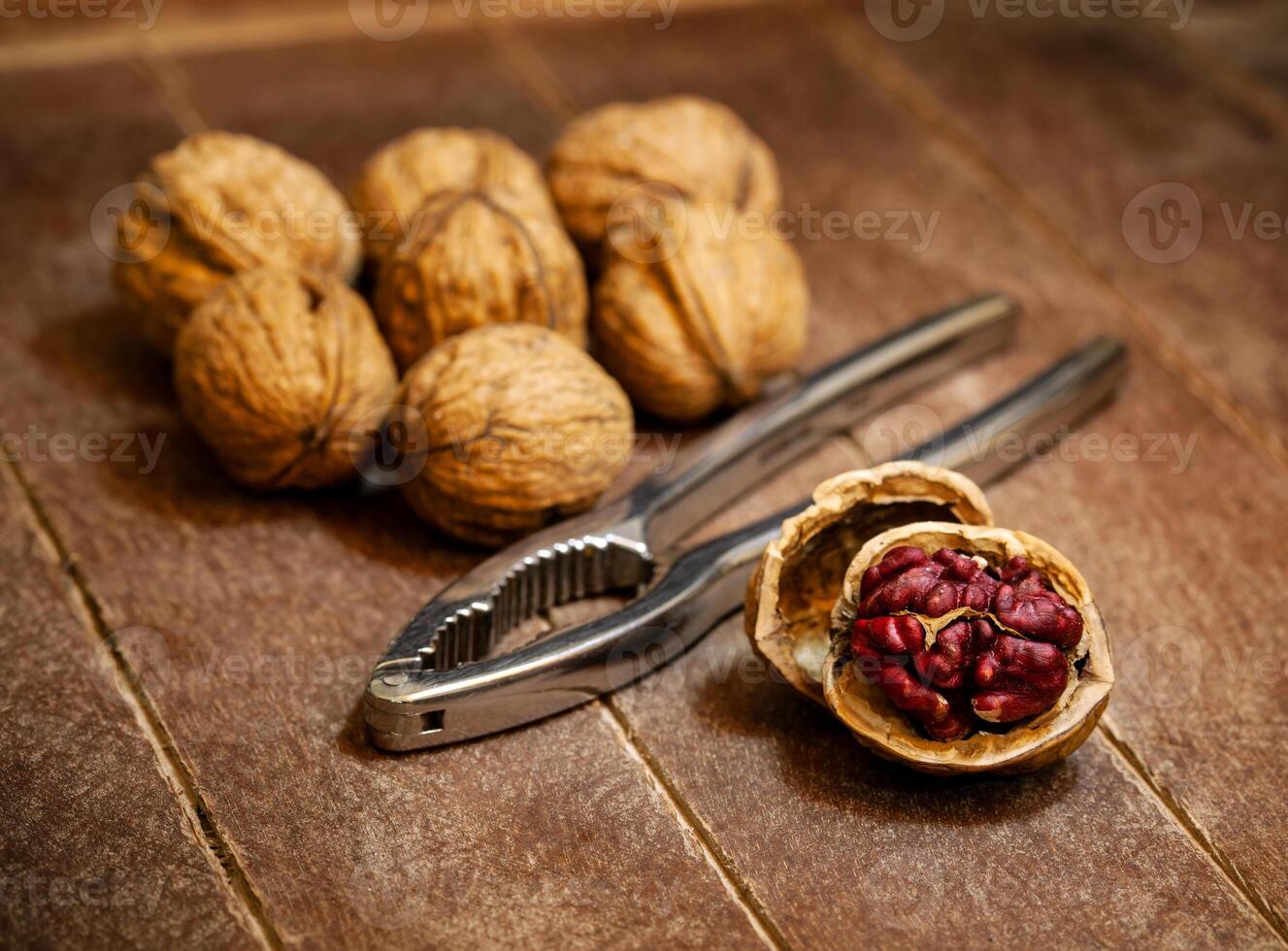 Red Danube Walnuts with silver nutcracker on wooden background photo