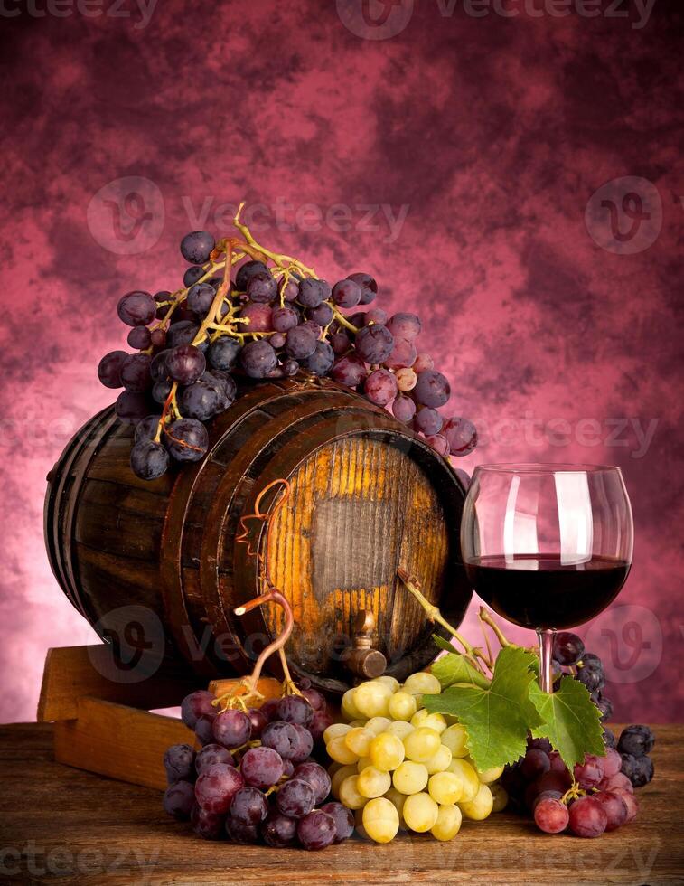 Red wine bottle and wine glass on wodden barrel photo
