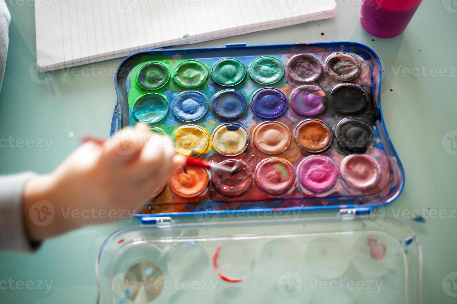 Hands of little girl painting with watercolors at home. Learn, education, happy childhood concept. photo