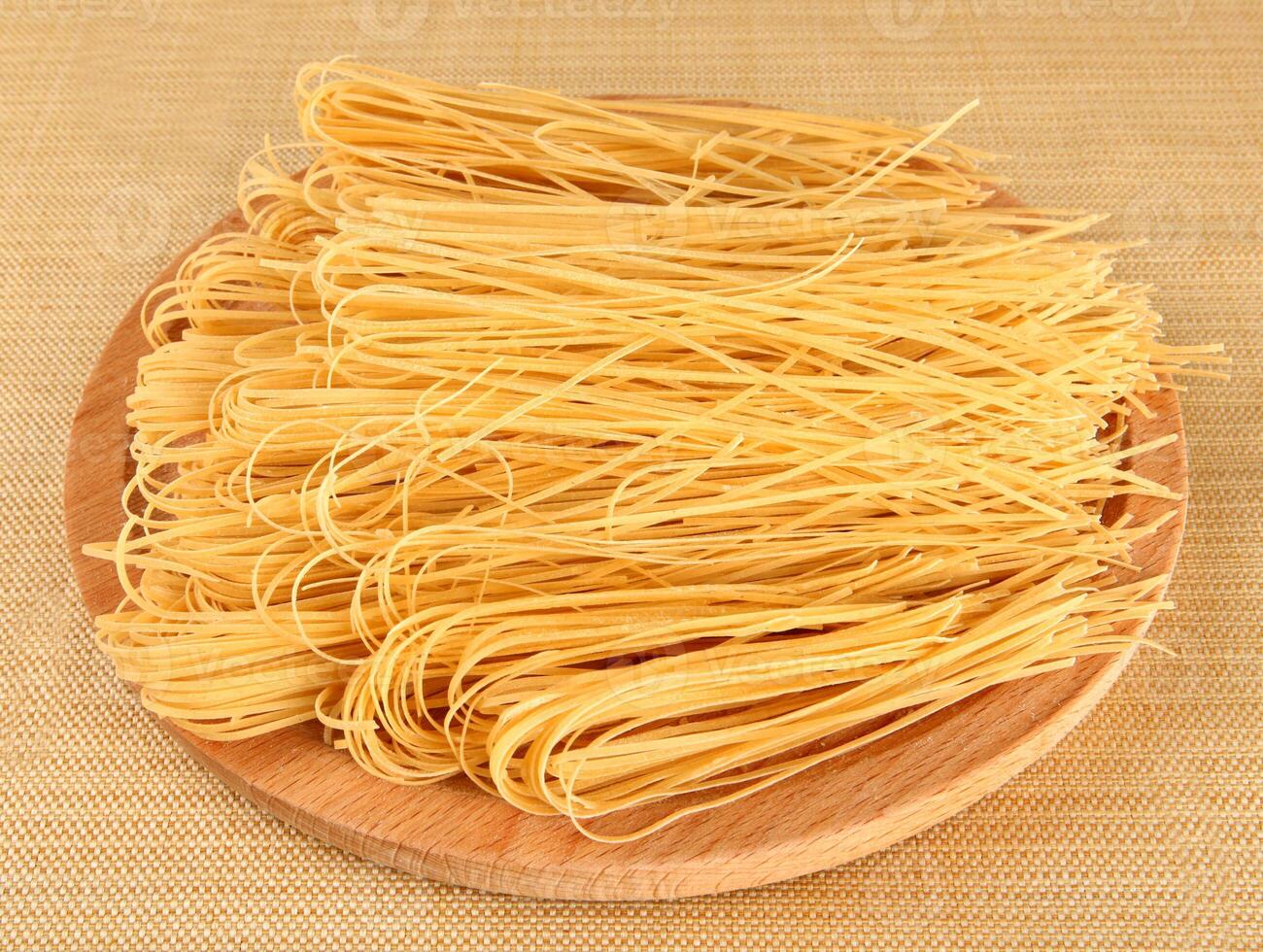 Raw italian pasta on wooden tray photo
