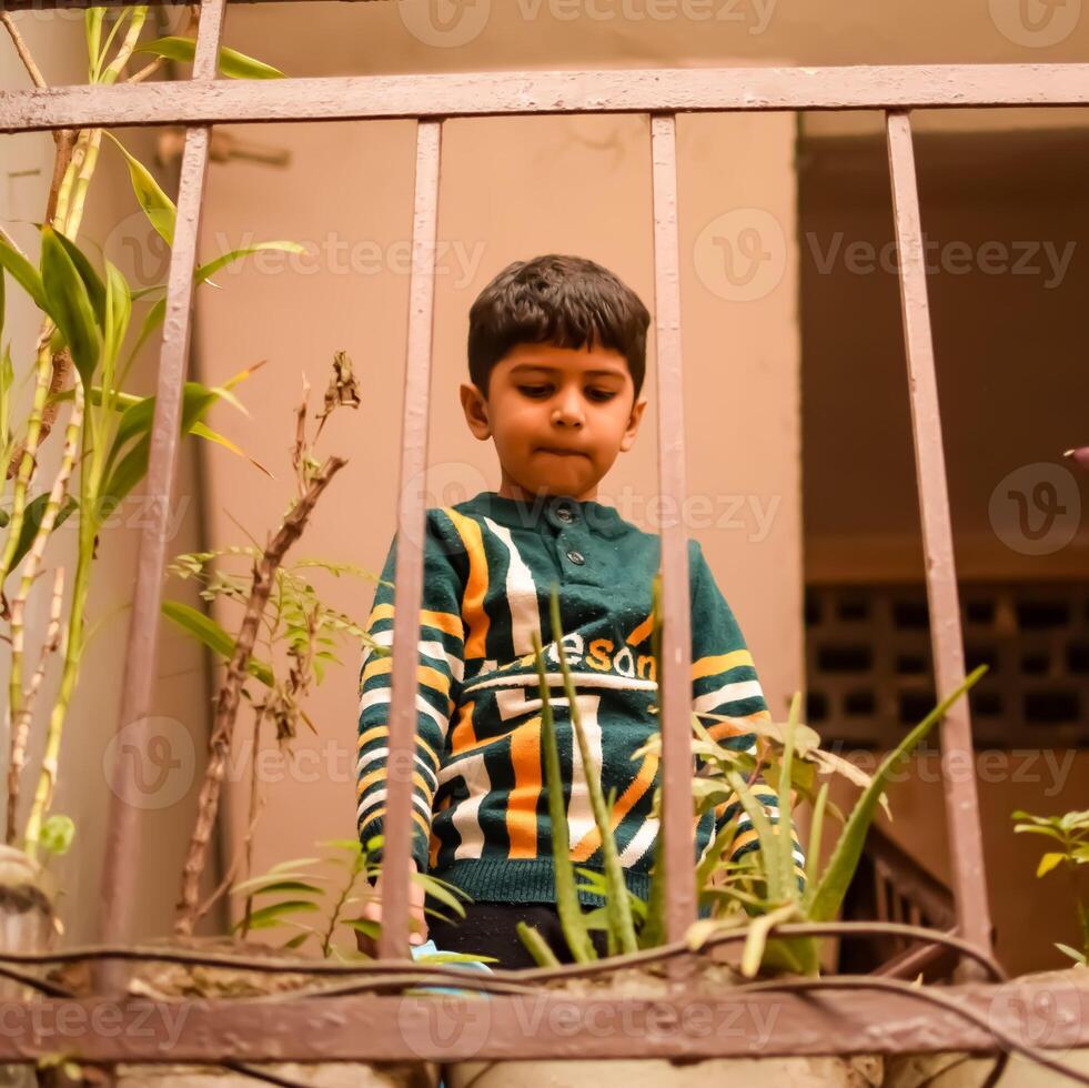 Cute 5 year old Asian little boy is watering the plant in the pots located at house balcony, Love of sweet little boy for the mother nature during watering into plants, Kid Planting photo