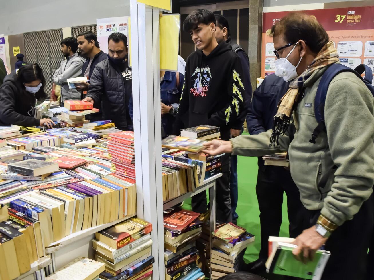 Delhi, India, February 17 2024 - Various age group people reading variety of Books on shelf inside a book-stall at Delhi International Book Fair, Books in Annual Book Fair at Bharat Mandapam complex photo