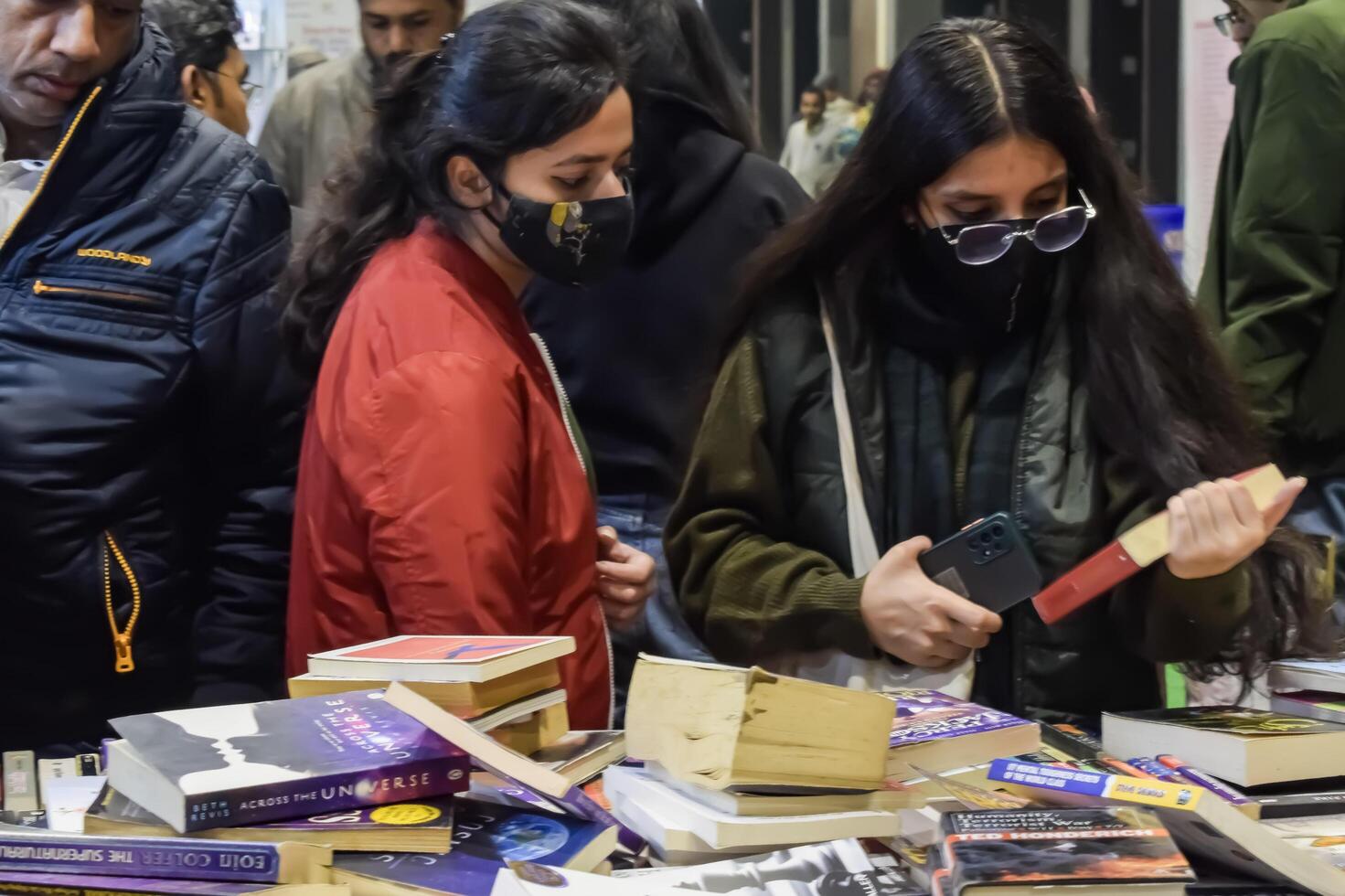 Delhi, India, February 17 2024 - Various age group people reading variety of Books on shelf inside a book-stall at Delhi International Book Fair, Books in Annual Book Fair at Bharat Mandapam complex photo