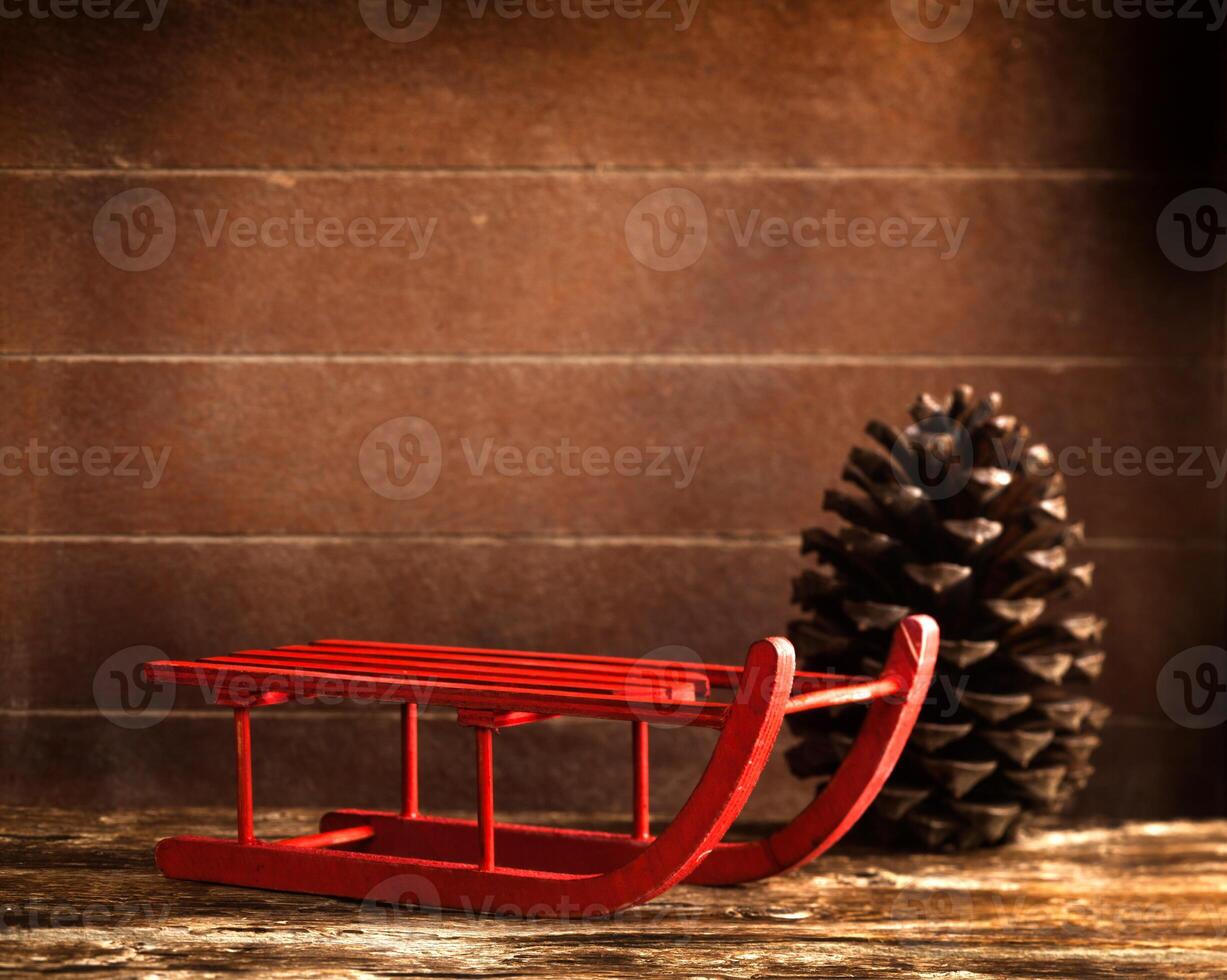Wooden red sled with brown pine cone photo