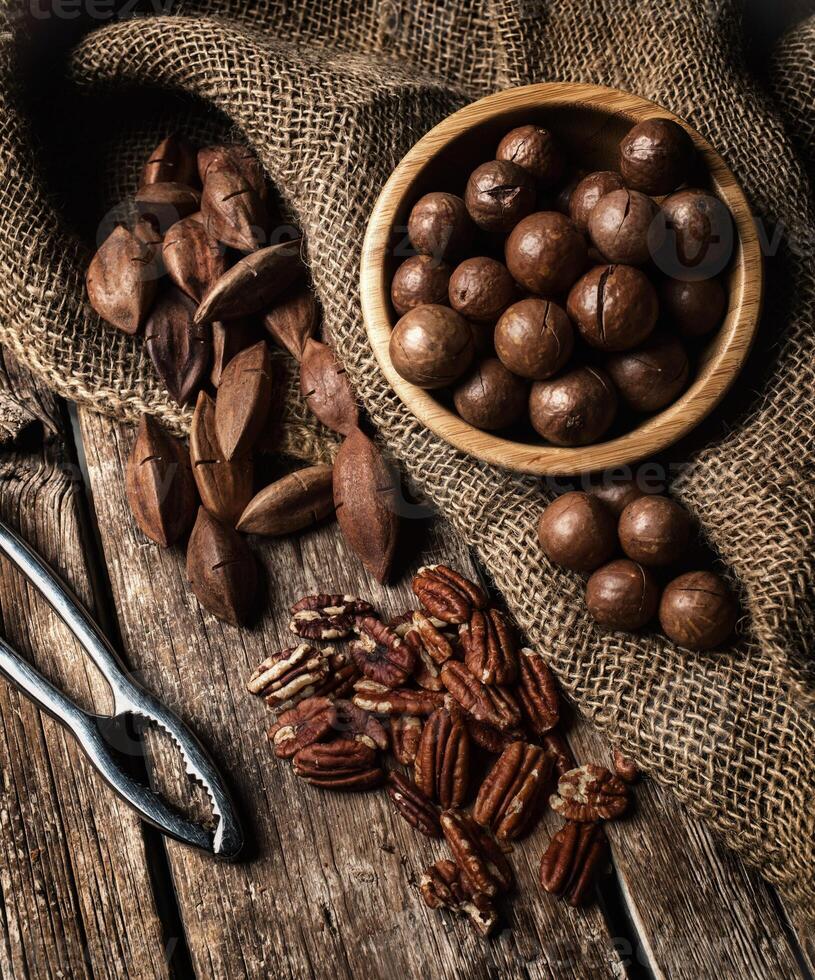Macadamia, Pecan and Pili nuts on wooden table photo