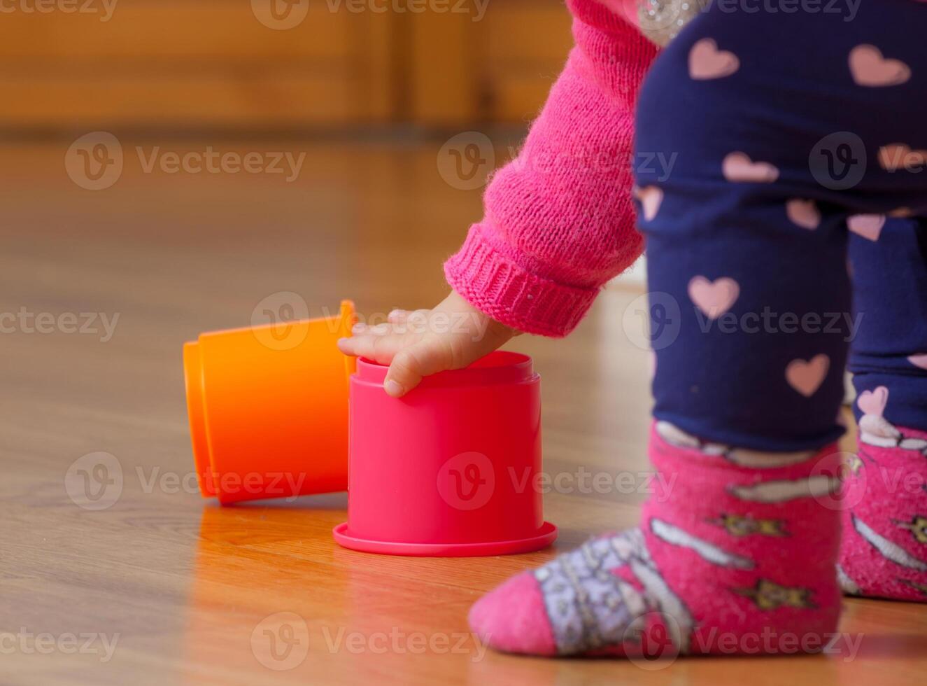 Toddler baby girl plays with colored cups photo