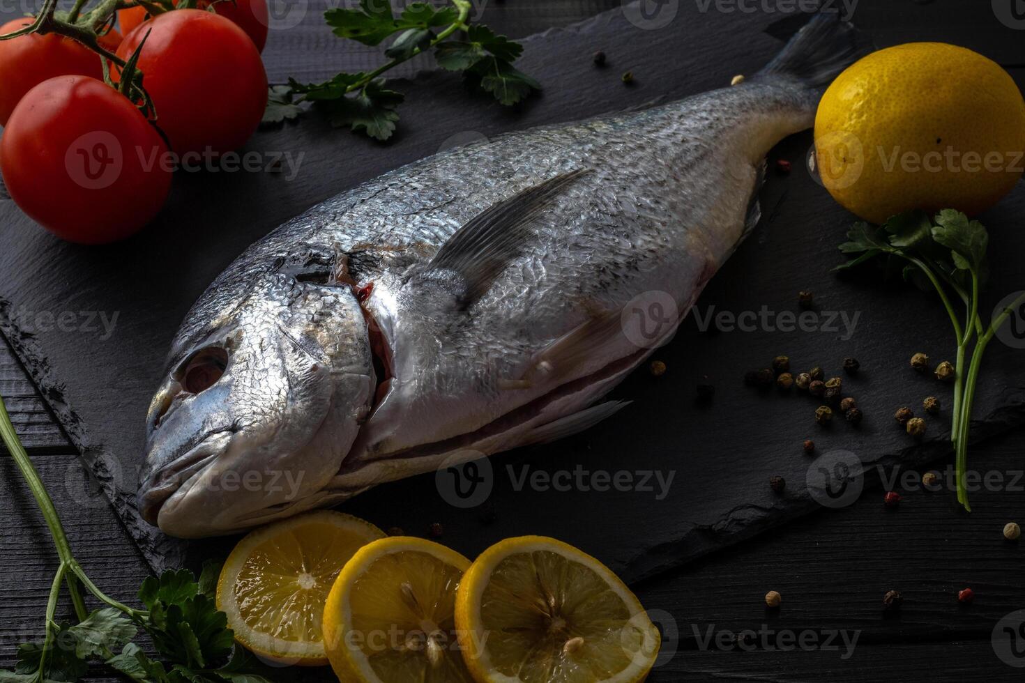 Sea bream or dorado sea fish herbs on dark slate background Top view photo
