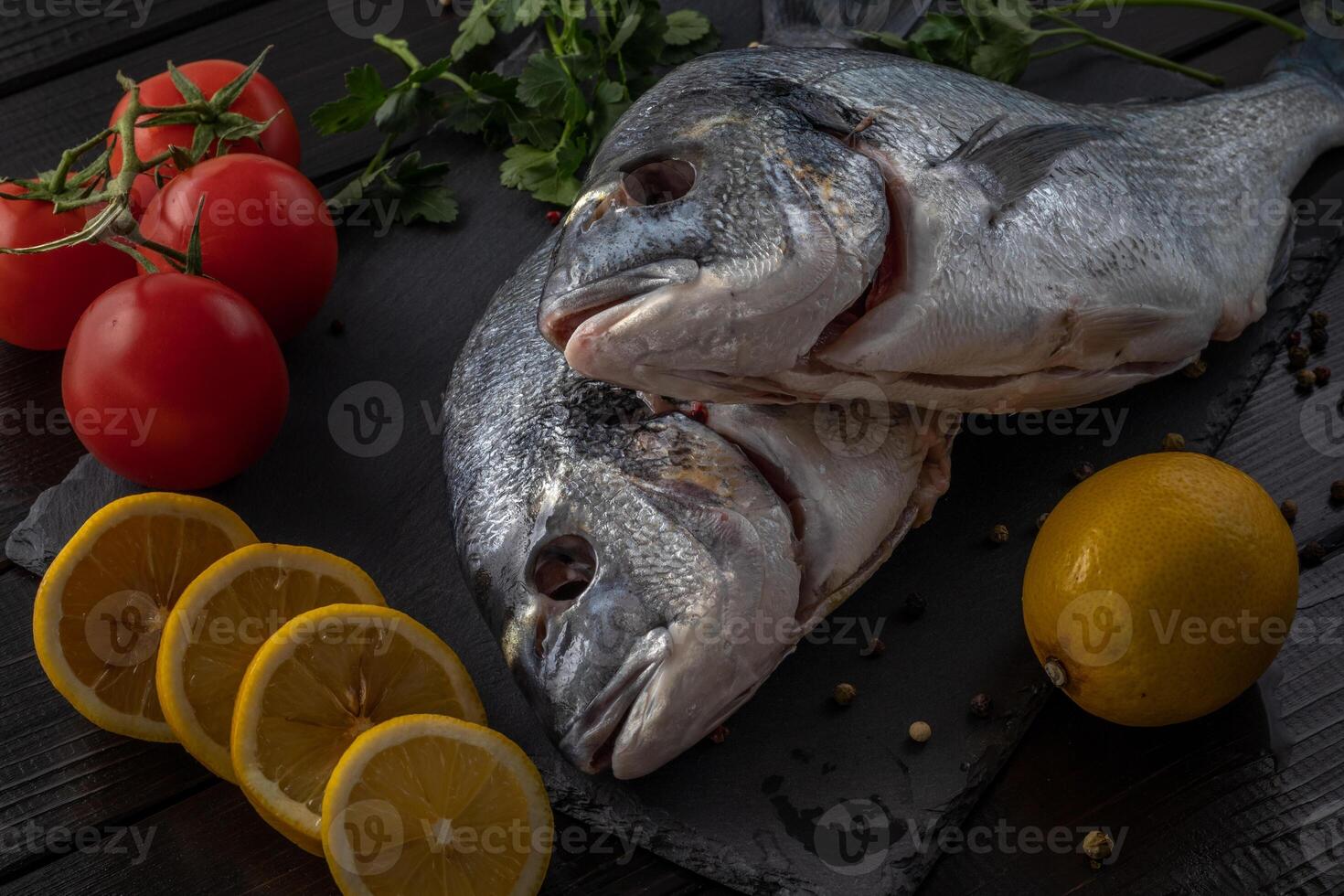 Sea bream or dorado sea fish herbs on dark slate background Top view photo