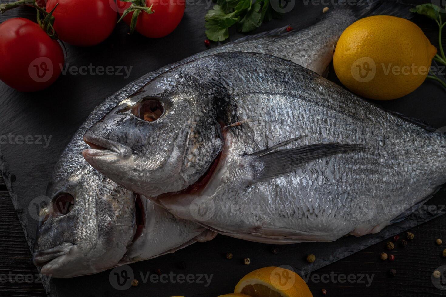Sea bream or dorado sea fish herbs on dark slate background Top view photo