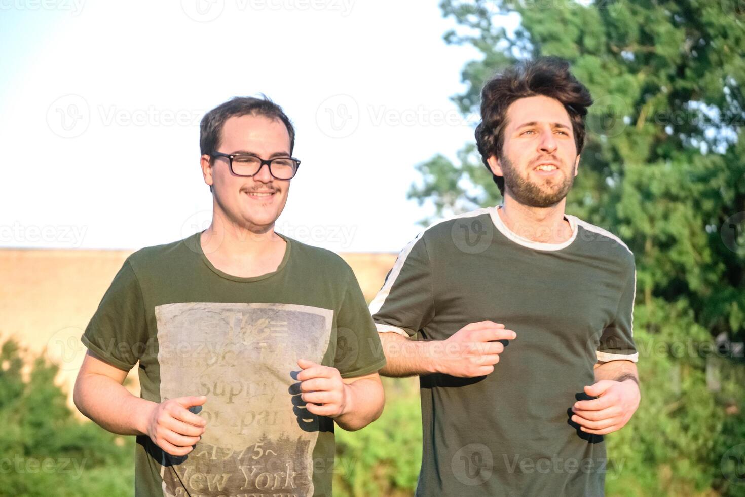 dos amigos corriendo con verde camiseta en parque foto