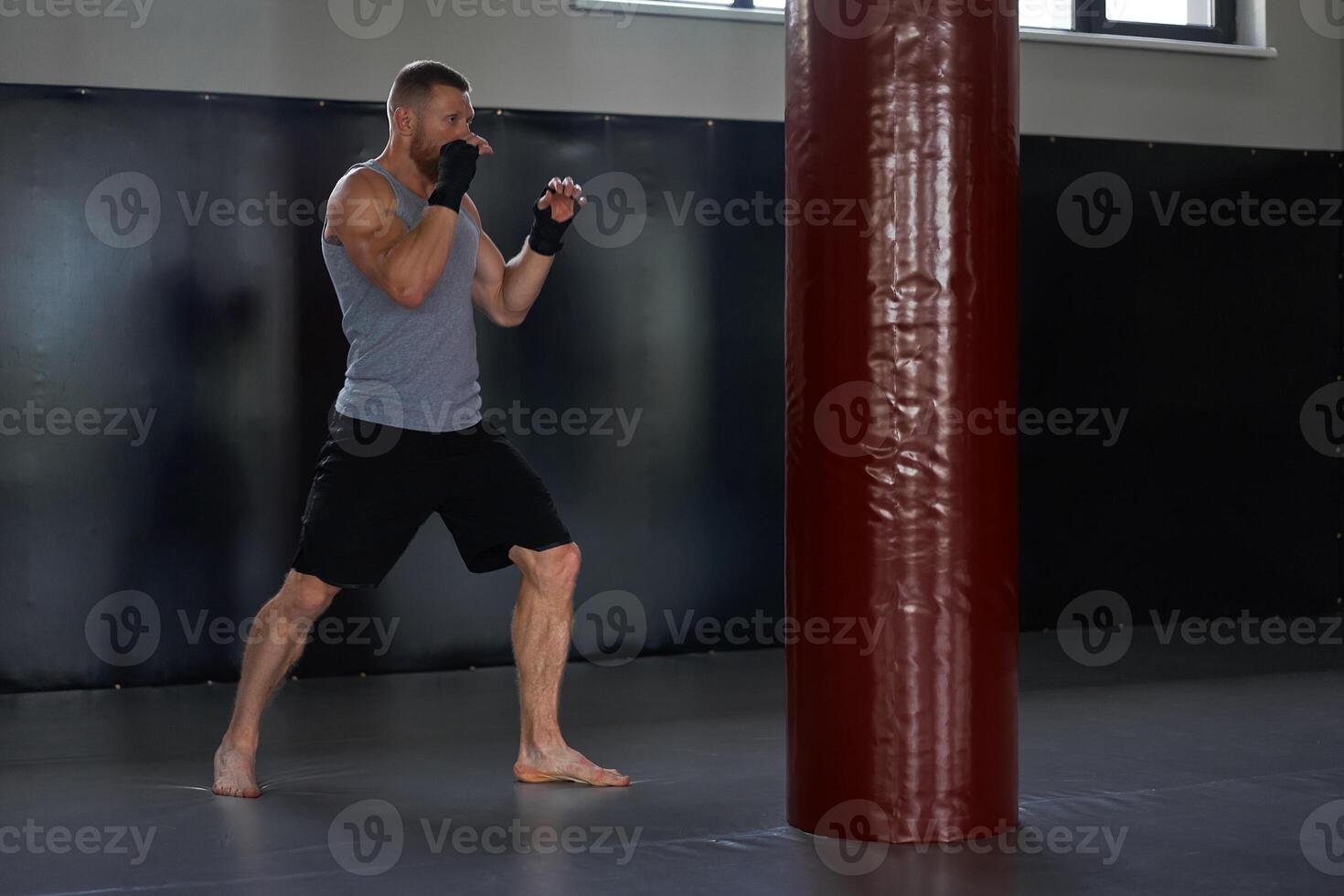 Kickboxer fighting with punch bag in health club photo