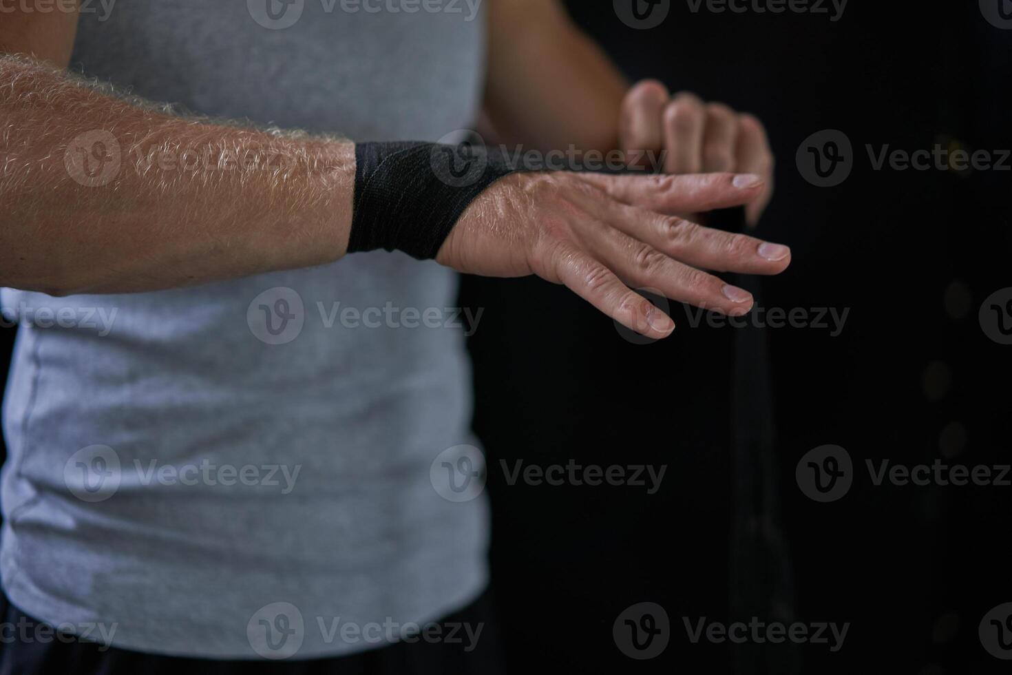 Anonymous kickboxer wrapping bandage on hand in gym photo