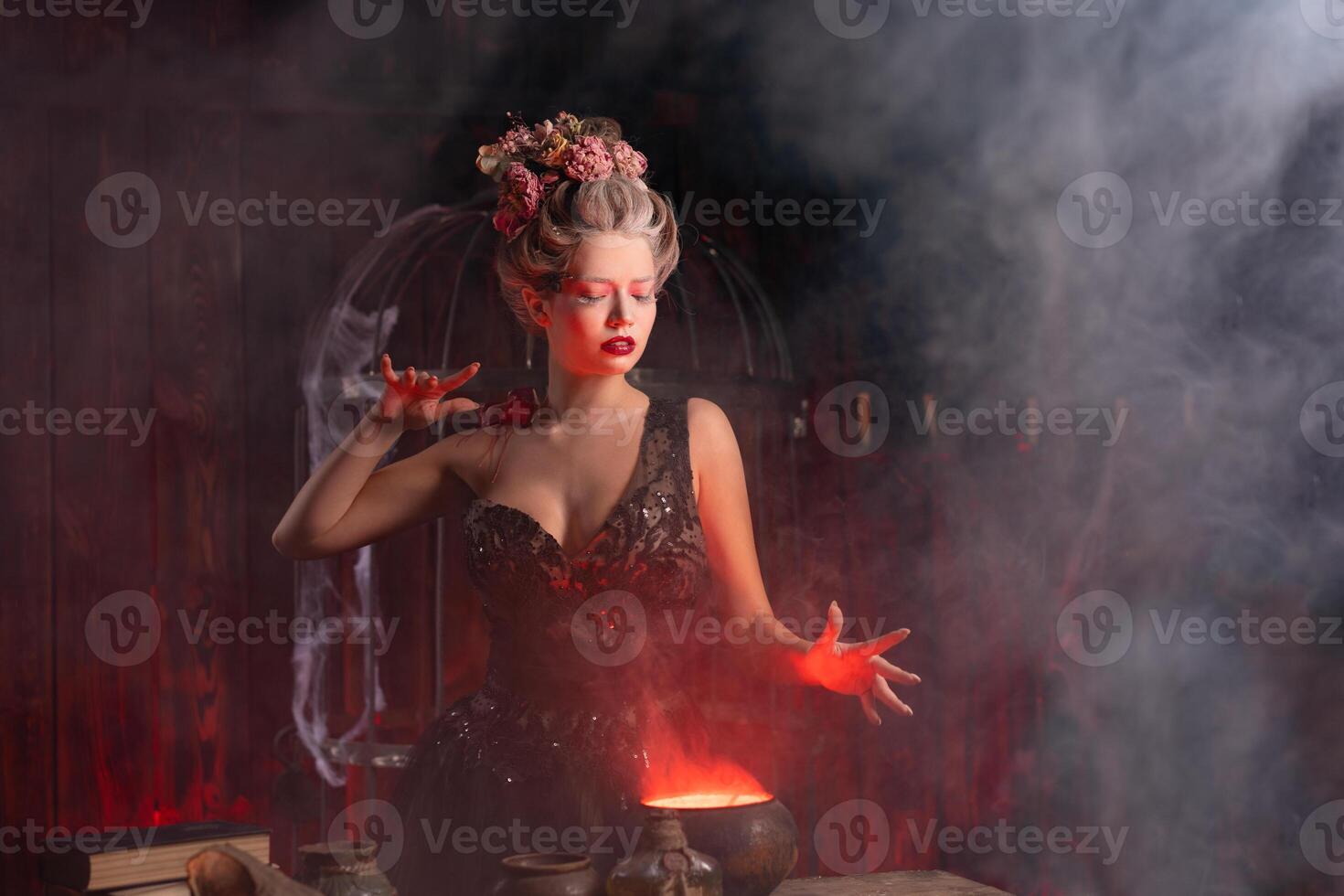 Halloween Witch with cauldron. Beautiful young woman conjuring, making witchcraft photo