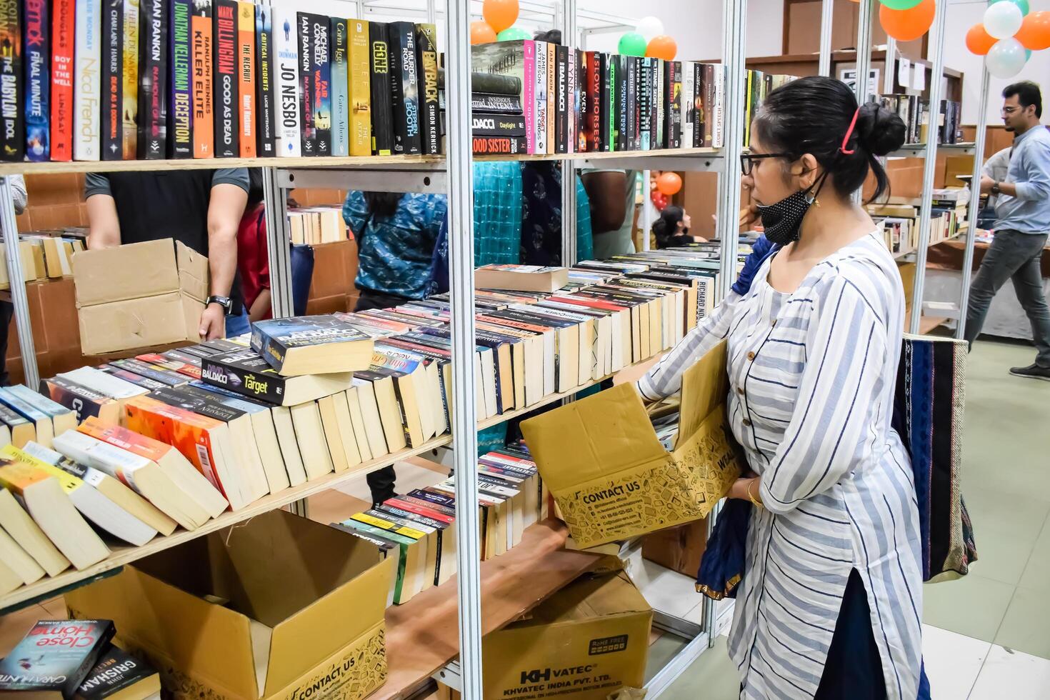 Delhi, India, September 09 2023 - Various age group people reading variety of Books on shelf inside a book-stall at Delhi International Book Fair, Selection of books on display in Annual Book Fair photo