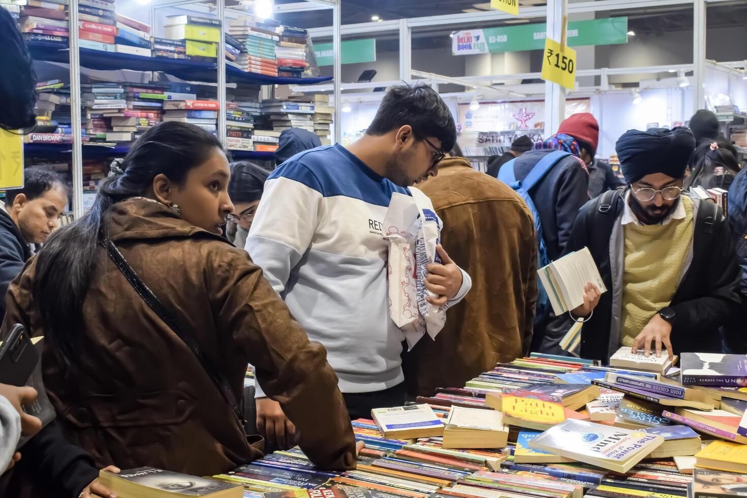 Delhi, India, February 17 2024 - Various age group people reading variety of Books on shelf inside a book-stall at Delhi International Book Fair, Books in Annual Book Fair at Bharat Mandapam complex photo