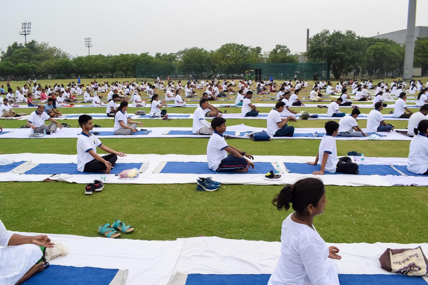 New Delhi, India, June 21, 2023 - Group Yoga exercise session for people at Yamuna Sports Complex in Delhi on International Yoga Day, Big group of adults attending yoga class in cricket stadium photo