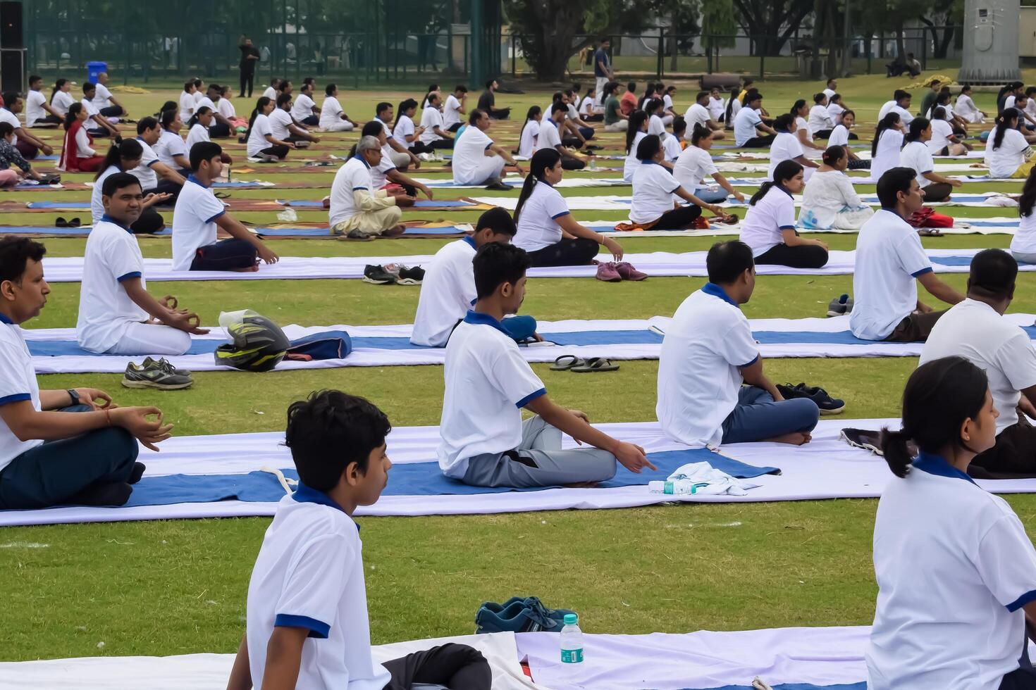 New Delhi, India, June 21, 2023 - Group Yoga exercise session for people at Yamuna Sports Complex in Delhi on International Yoga Day, Big group of adults attending yoga class in cricket stadium photo
